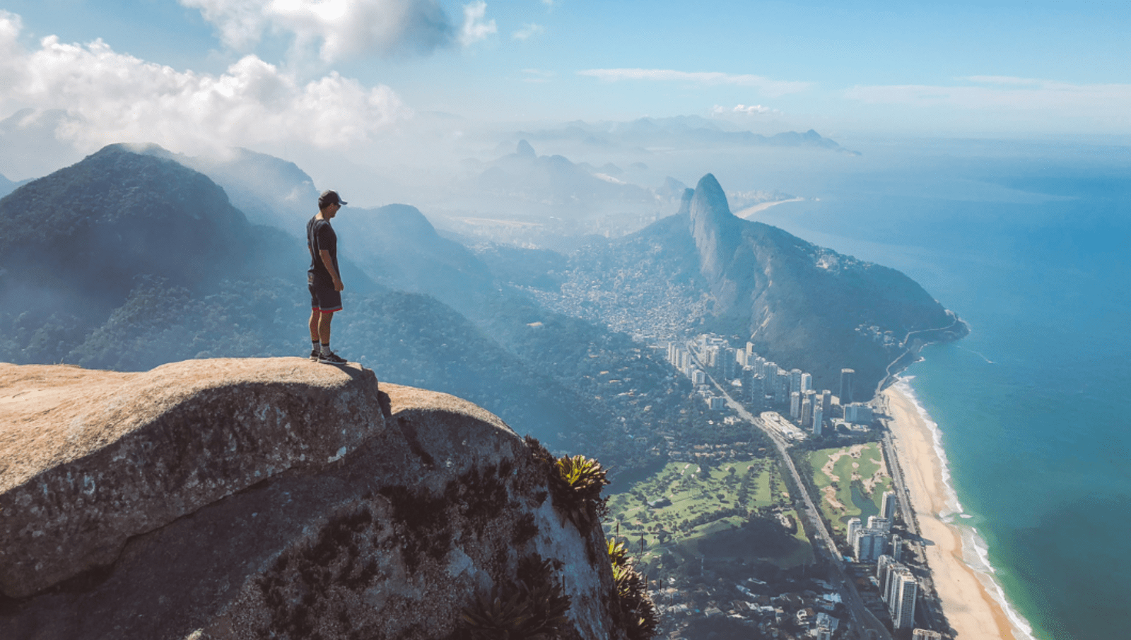 Man standing on a rock on a tall mountain overlooking rio