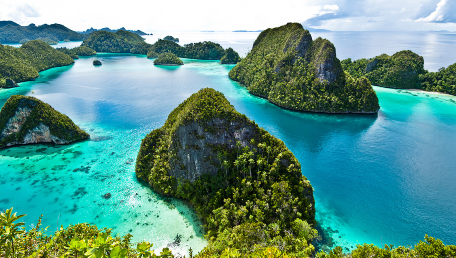 A group of tall, small islands covered in trees and surrounded by bright, blue water