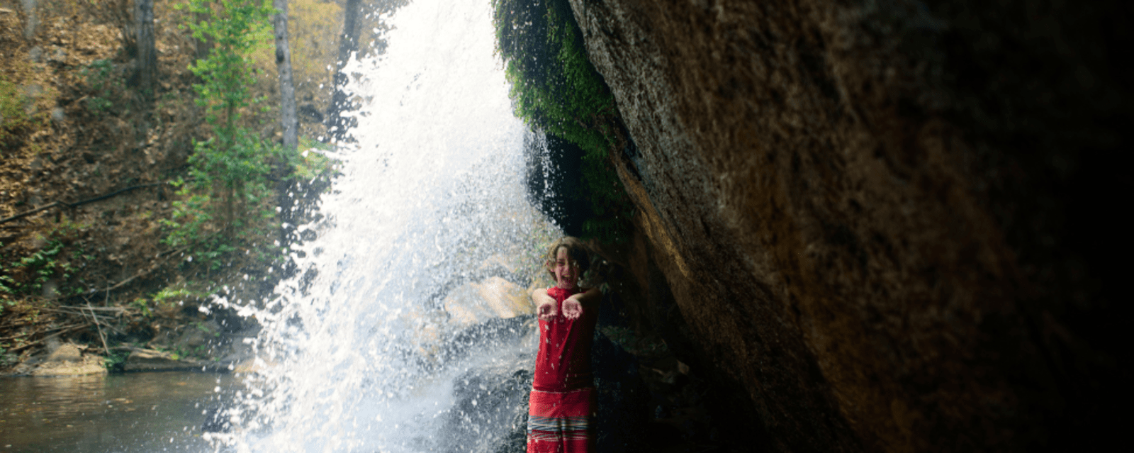 Young boy standing under Bua Tong Waterfall in Thailand