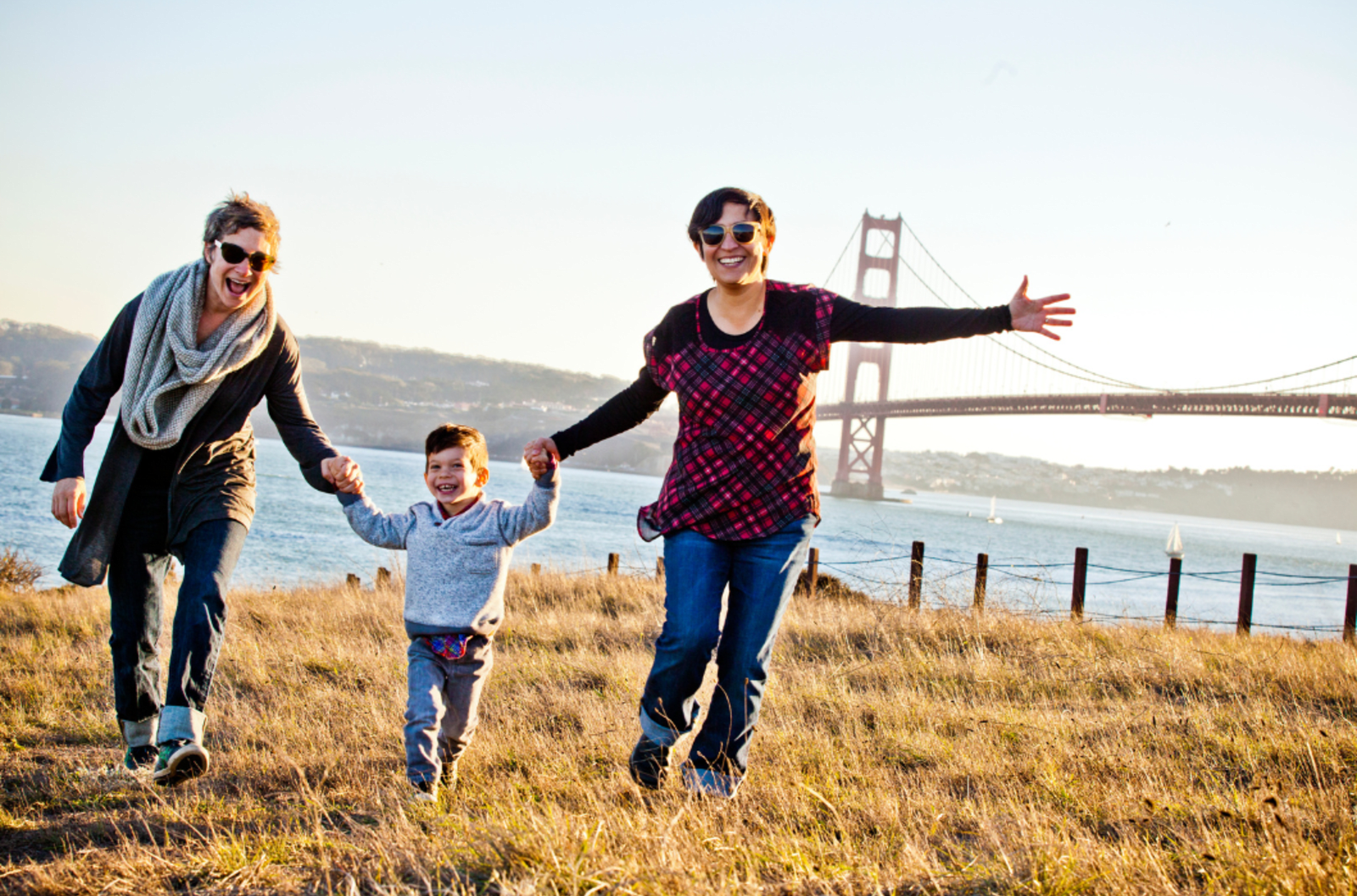 Two women and a young boy holding hands in front of the Golden Gate Bridge in San Francisco