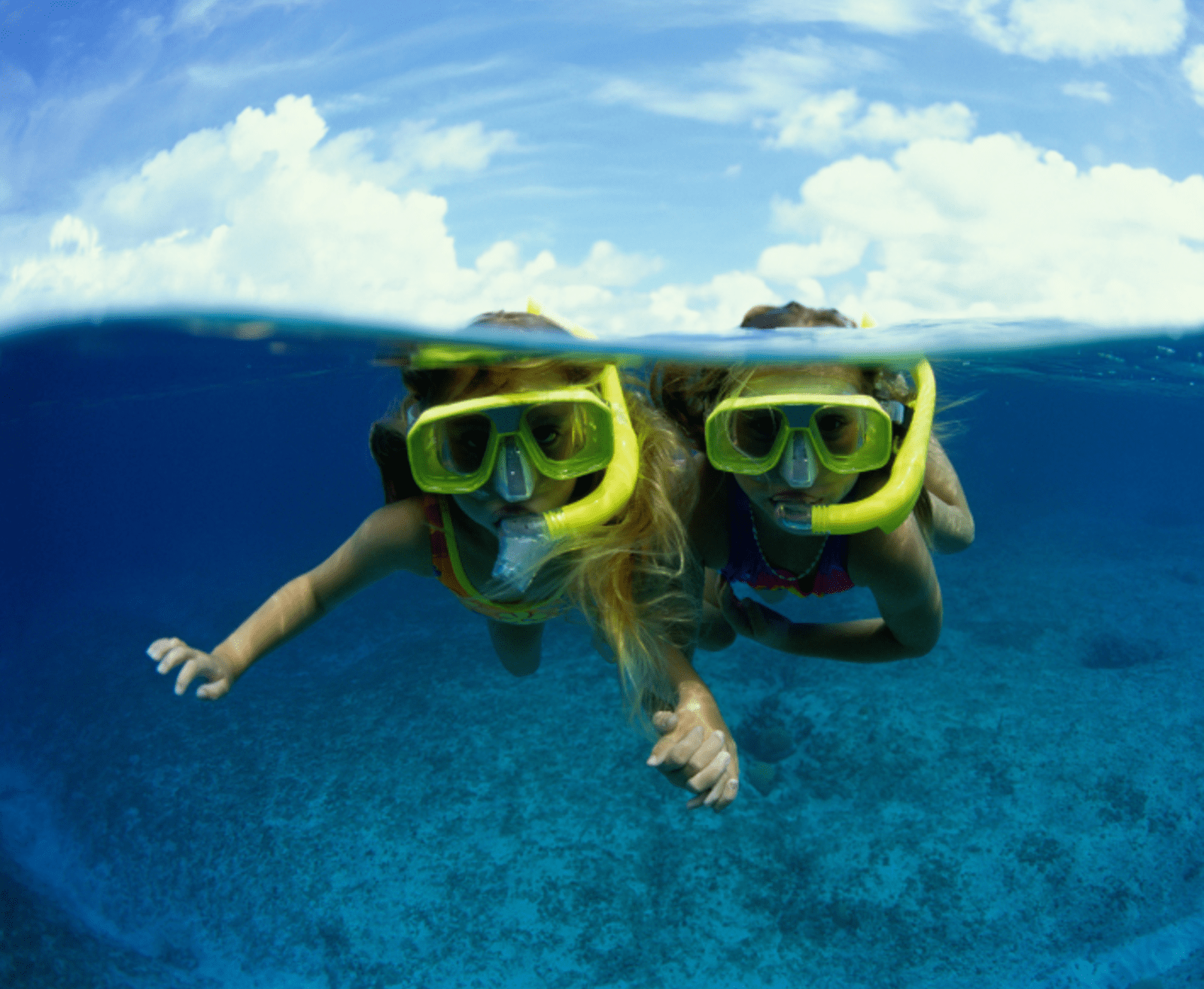 Two kids snorkelling in clear, blue water