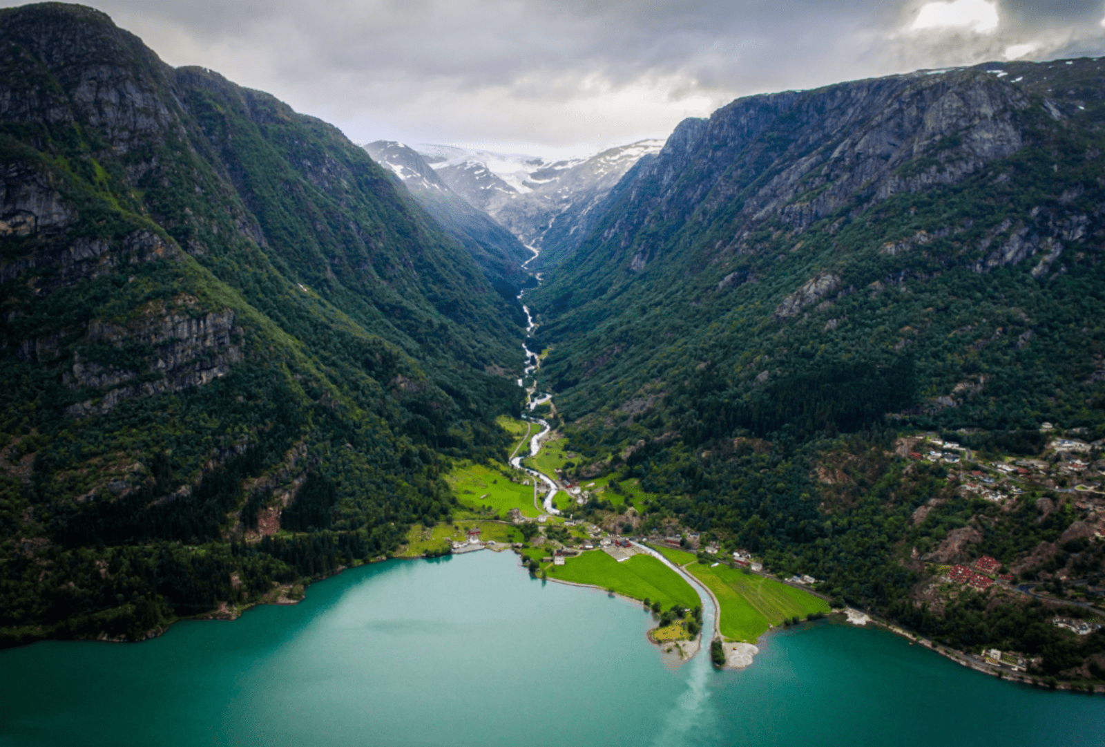 Aerial view of a river winding down a valley from mountains into a Norwegian Fjord