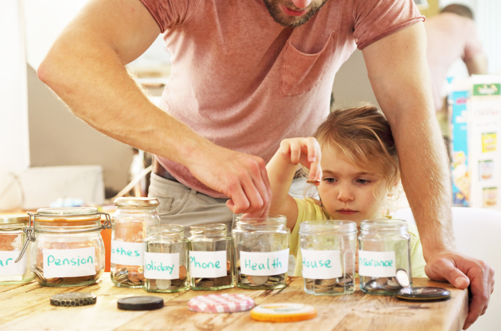 Parent and young child putting coins into labelled money jars