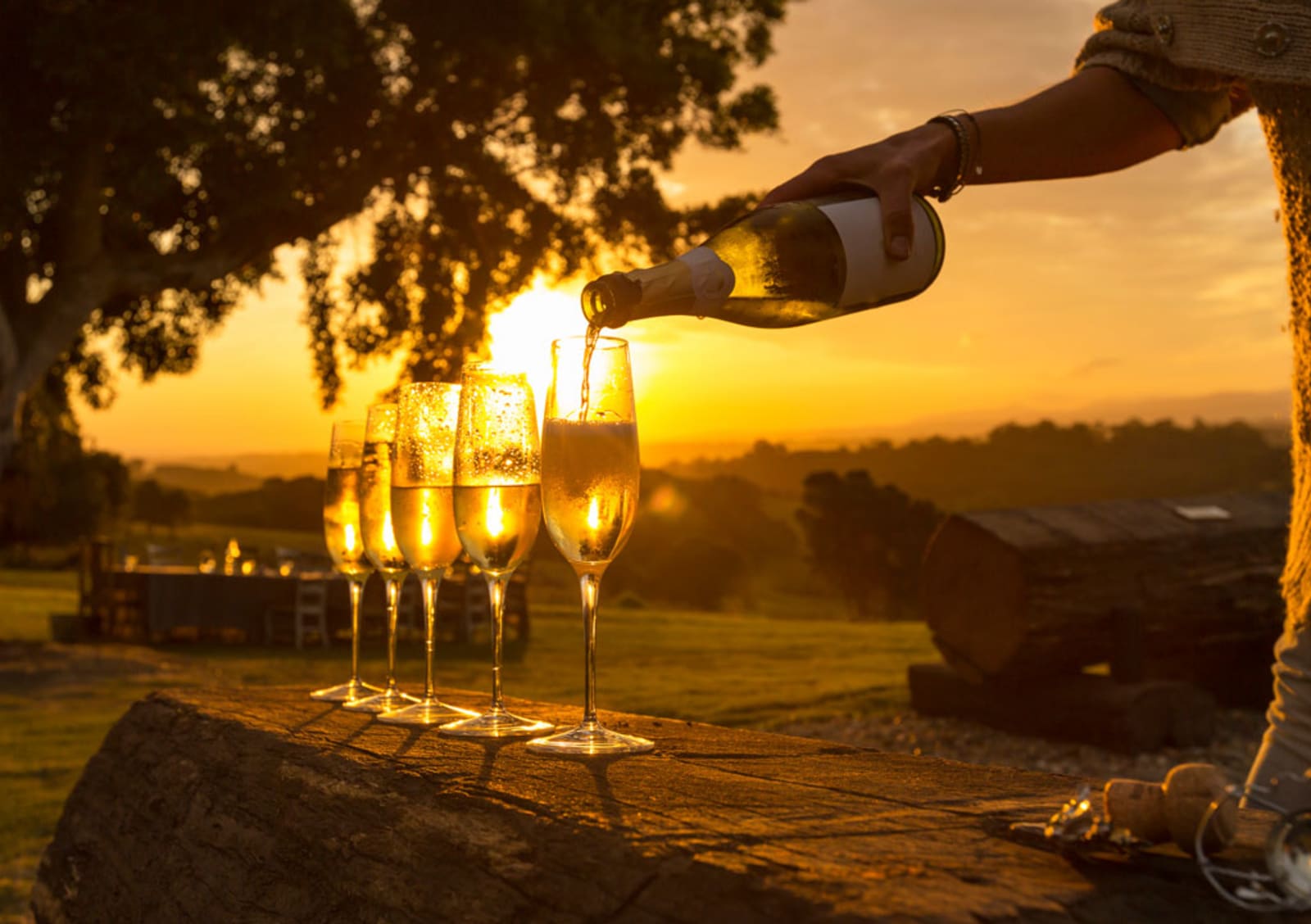 Wine being poured into glasses at sunset
