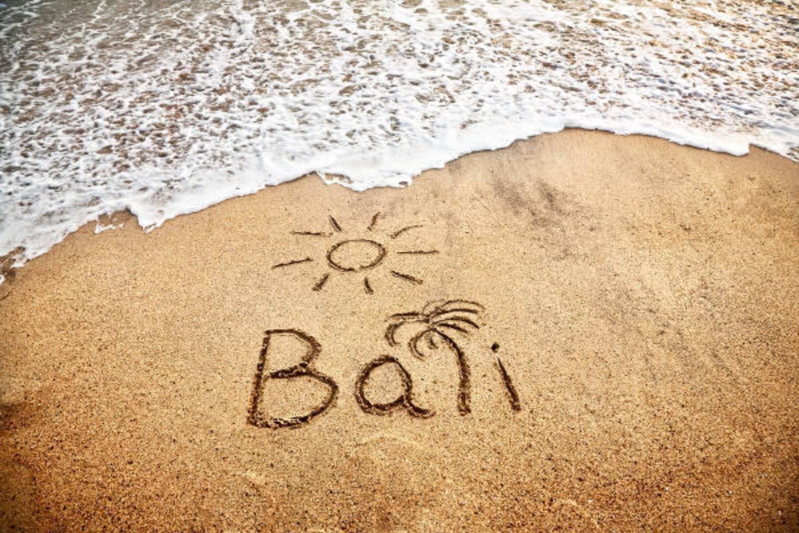 Bali written in the sand with a palm tree for the "L", and a cartoon sun