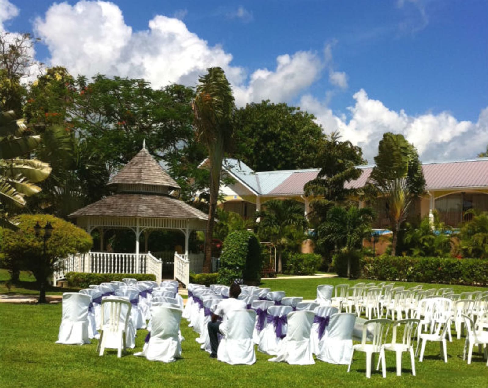 Wedding ceremony - white chairs setup pointing to a gazebo in a tree-lined field