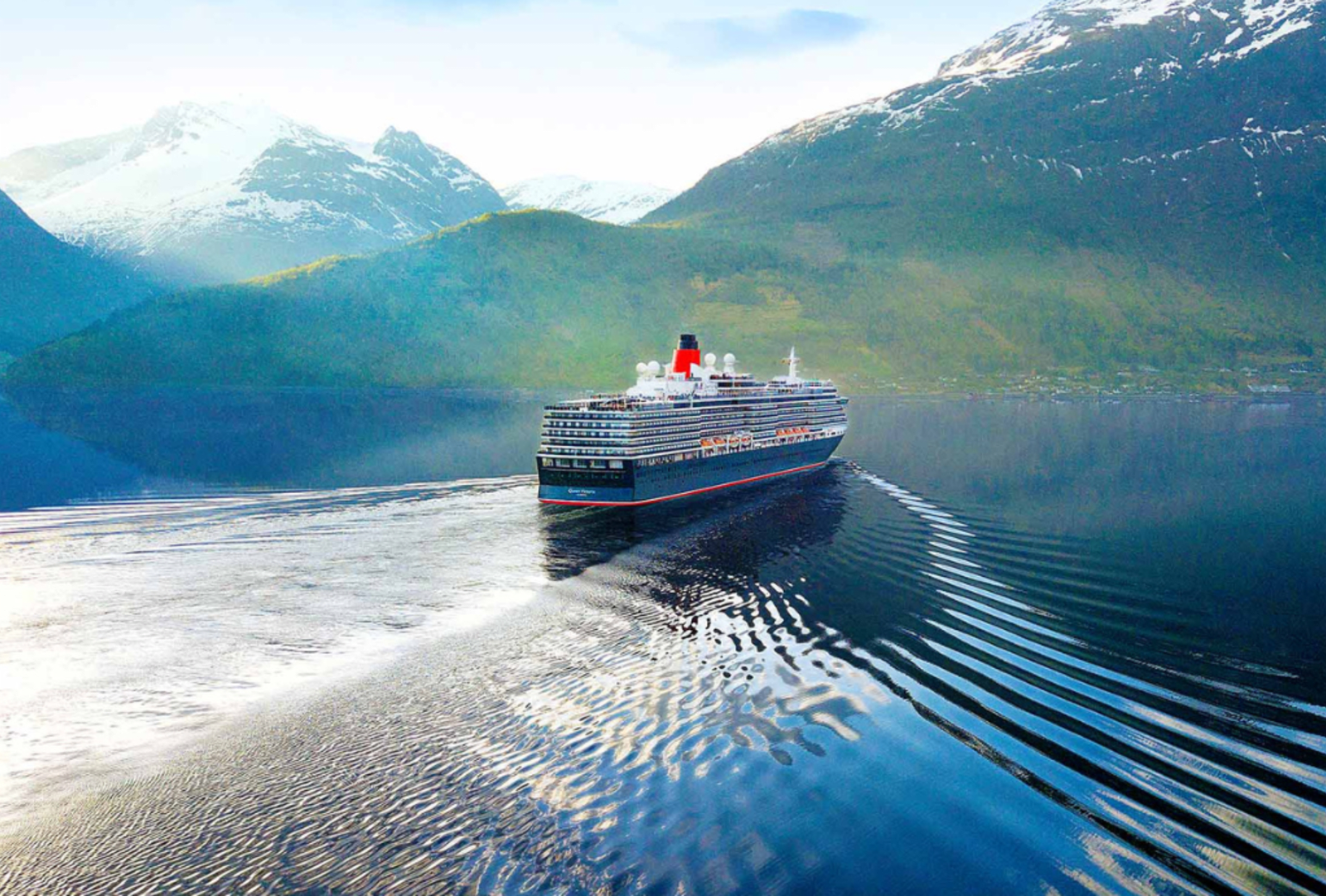 A cruise ship sails on calm waters with a mountainous background
