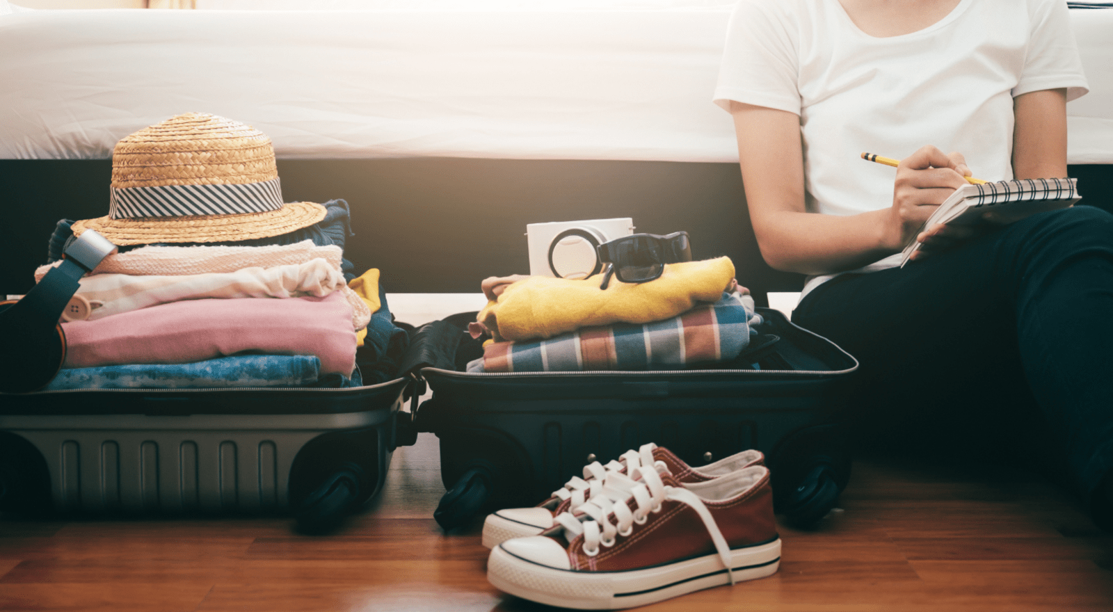 A woman marks off a checklist with items stacked in a suitcase