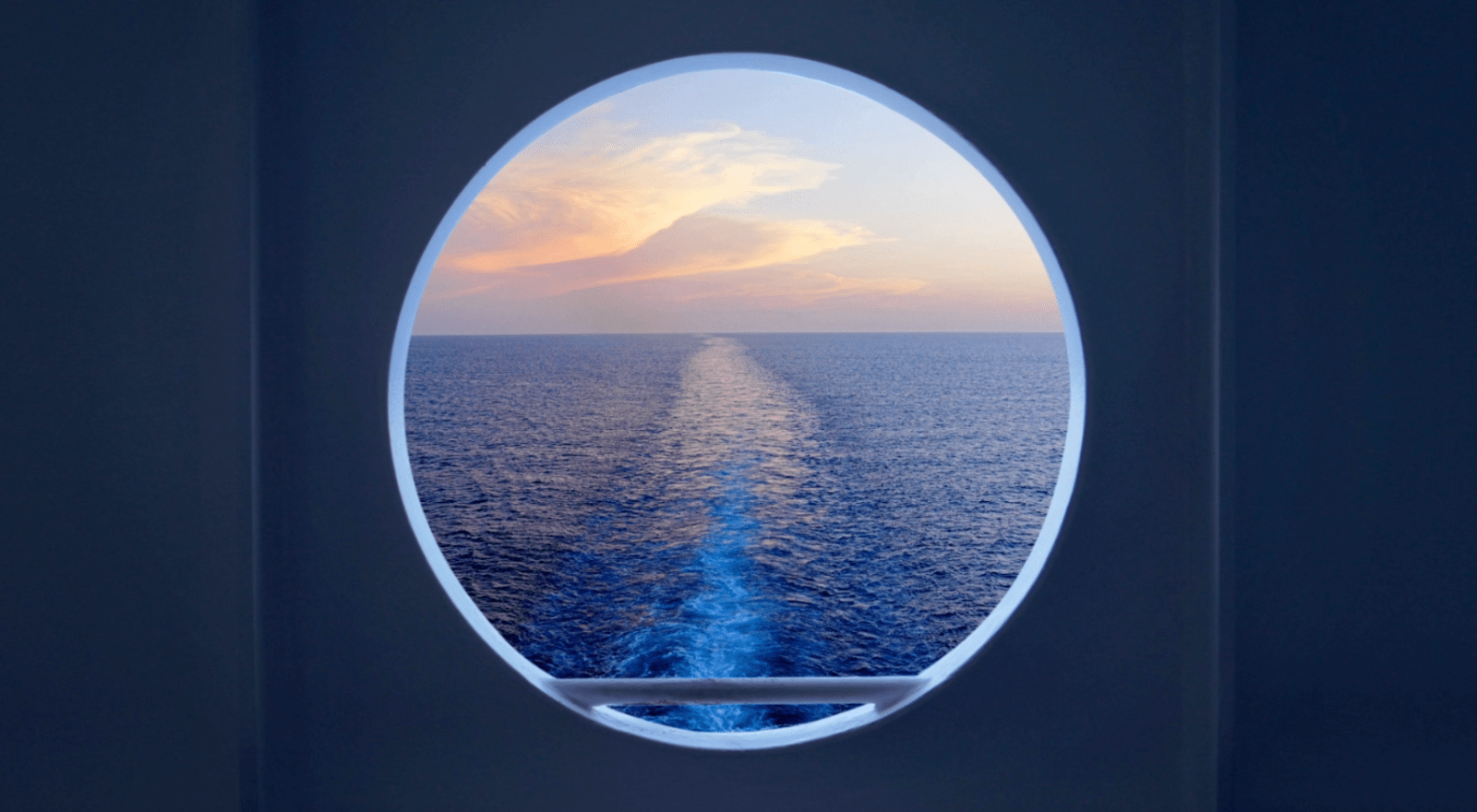 A ship's wake at sunset viewed through a porthole