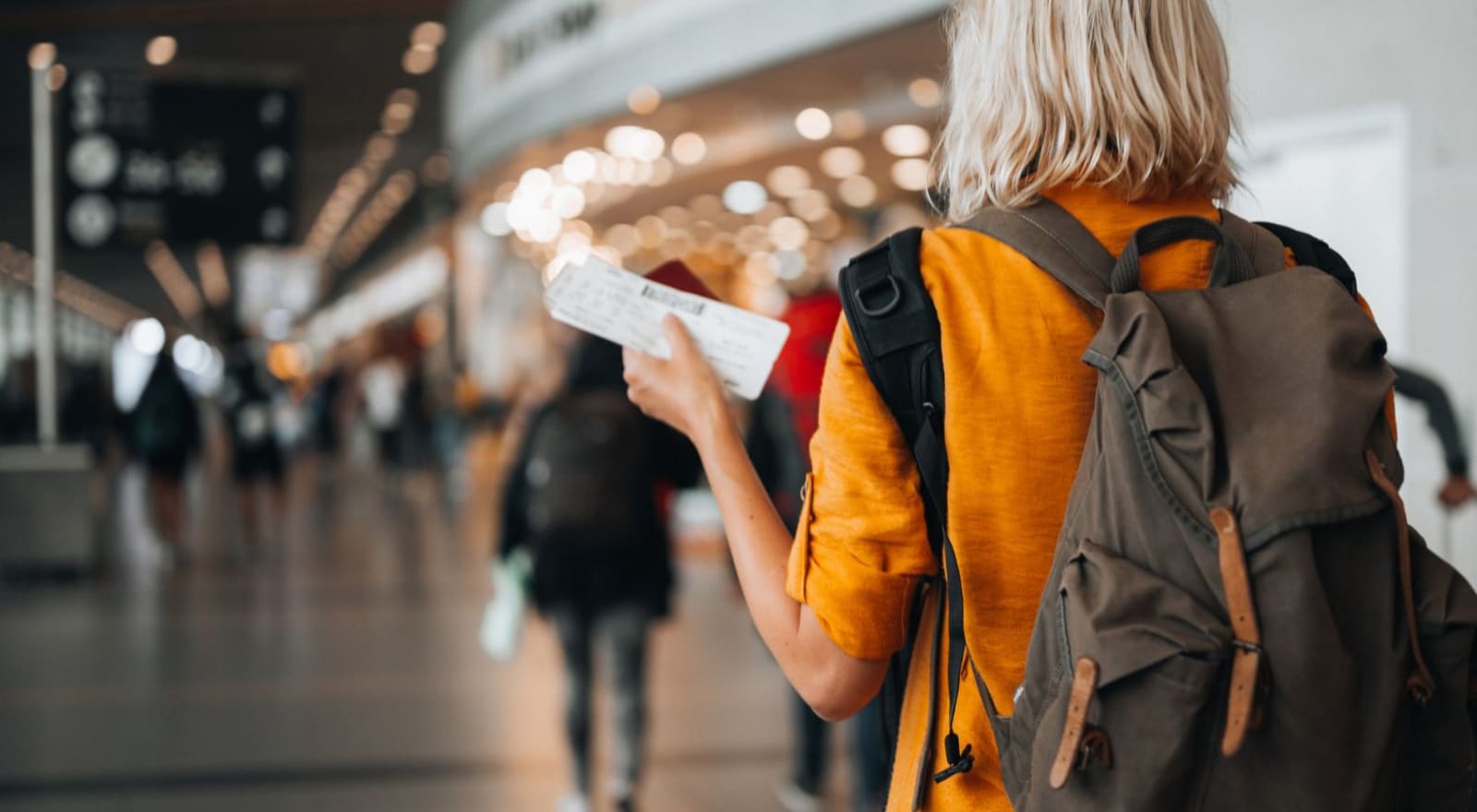 lady walking through airport holding boarding pass in hand