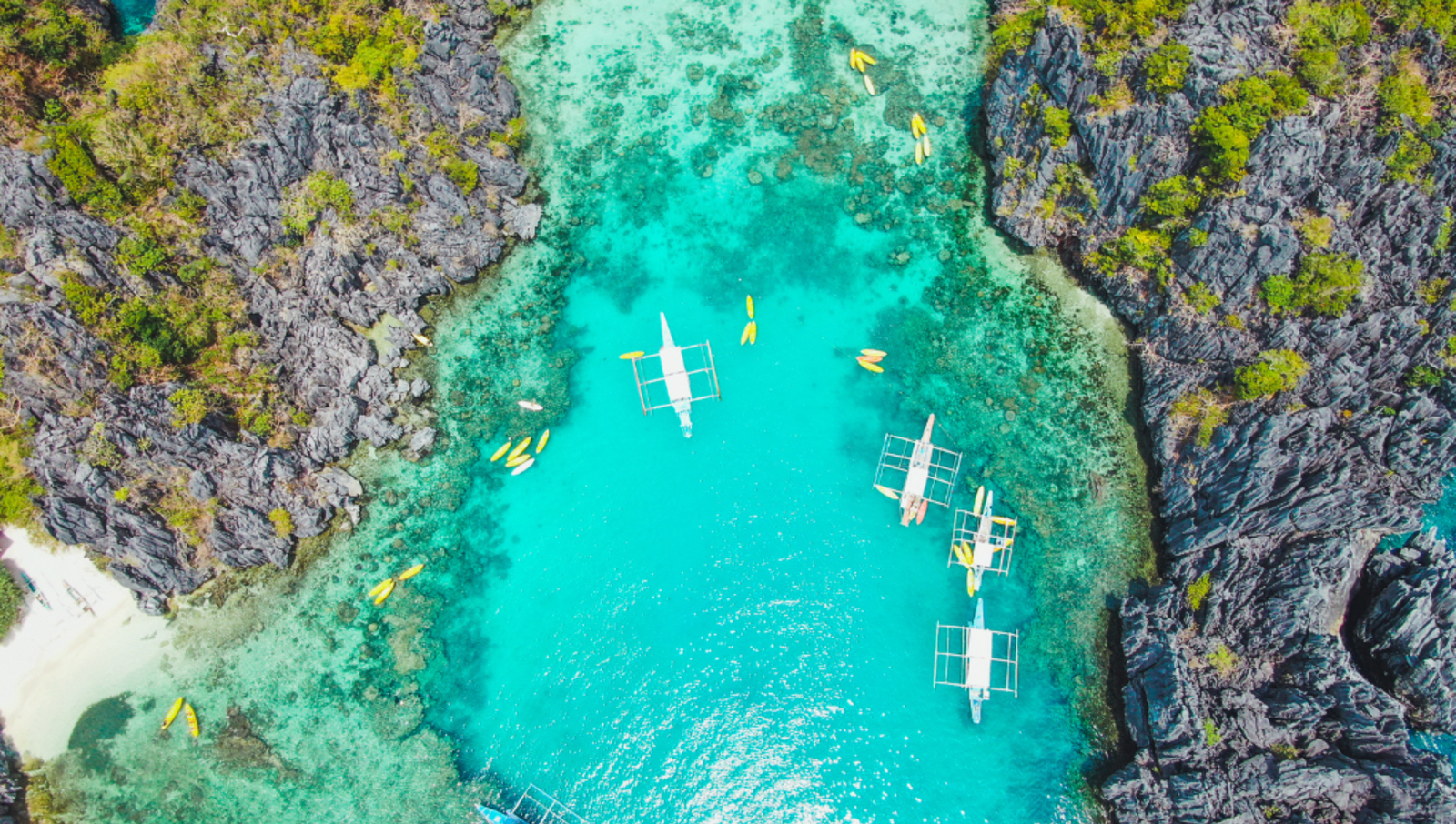 Kayaks in the crystal blue waters in El Nido Philippines between cliffs