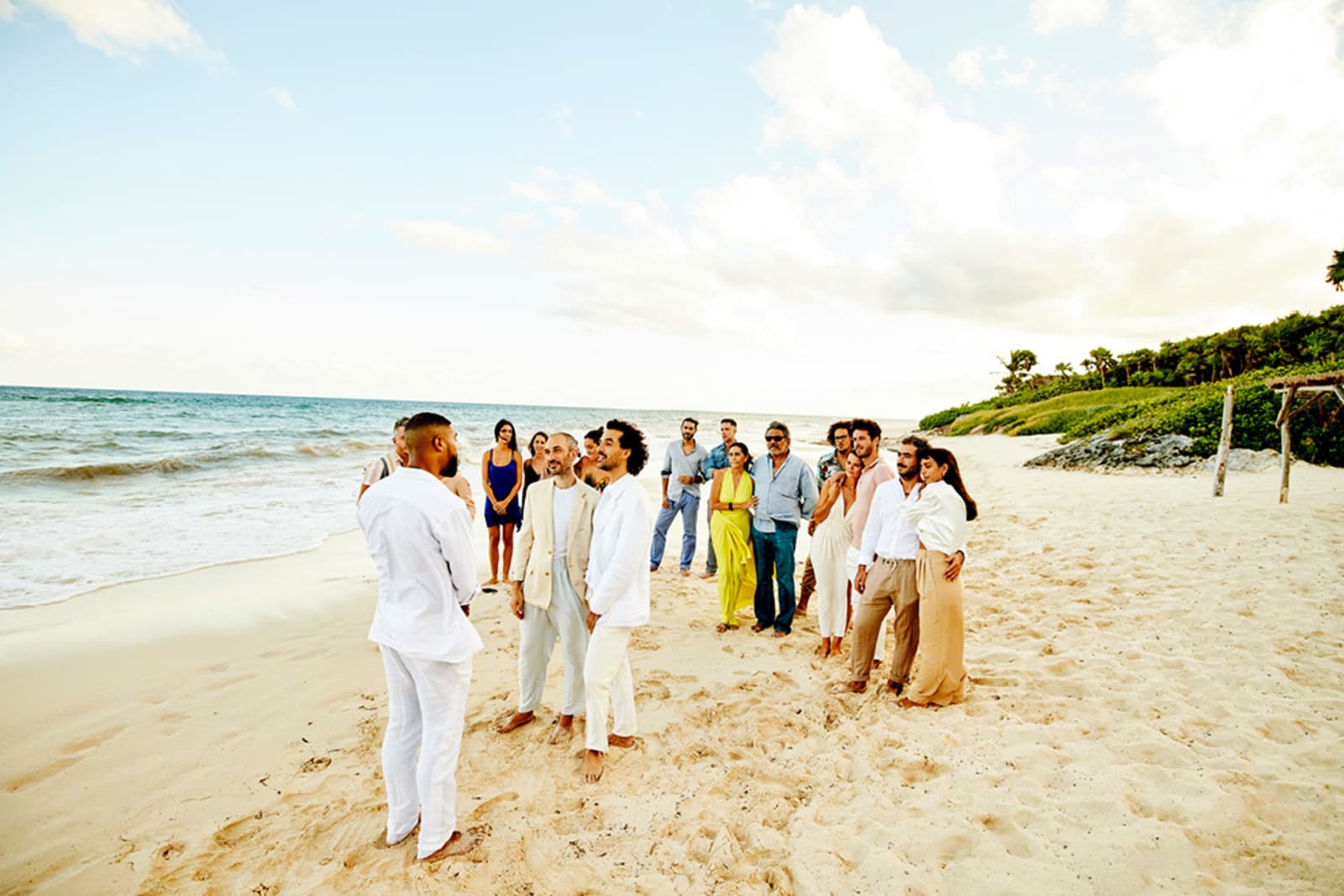 A small group of guests attend a destination wedding on a beach