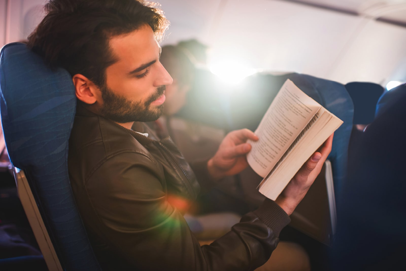 Man reading a book while on an airplane
