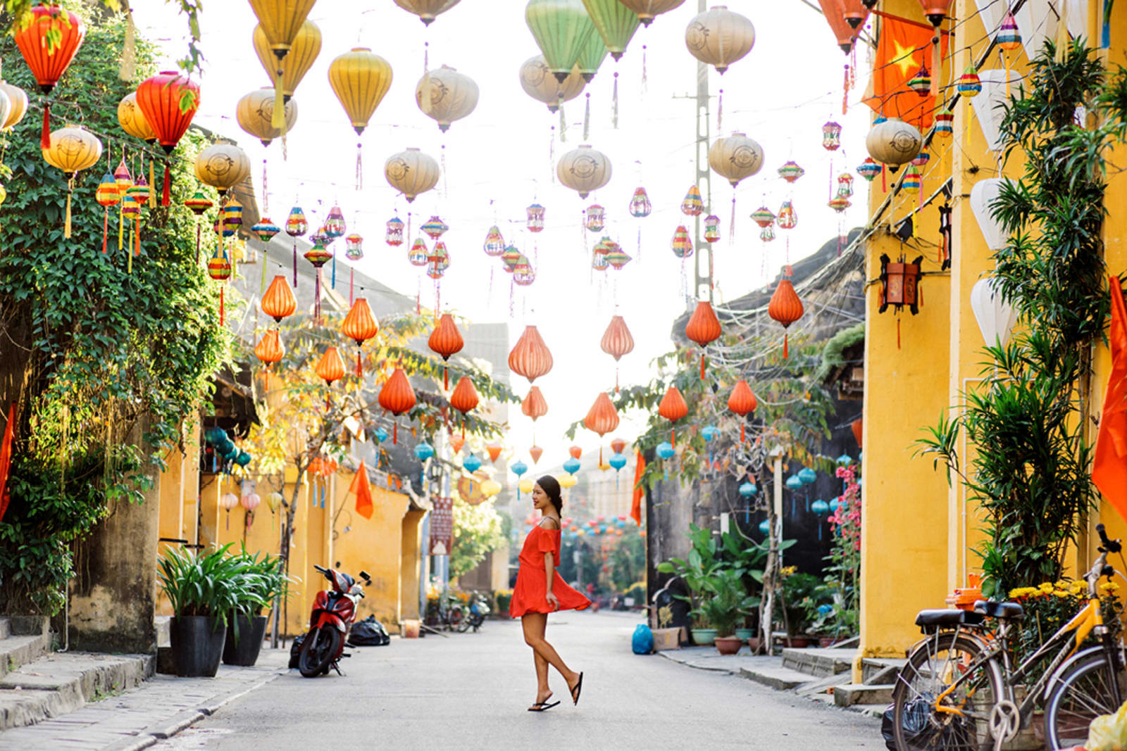 A woman stands under strings of lanterns on a street in Vietnam