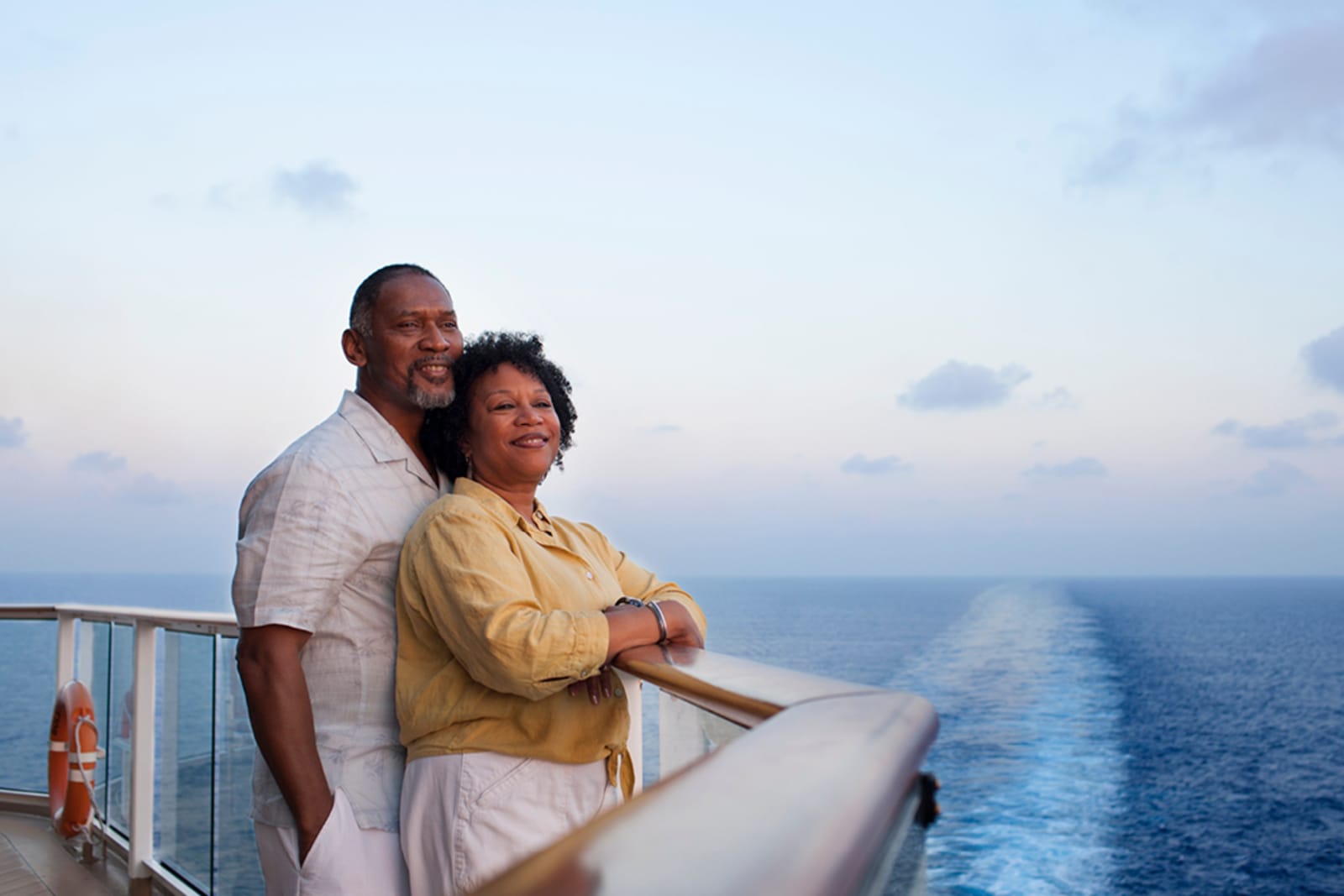 A senior couple standing on the deck of a cruise ship