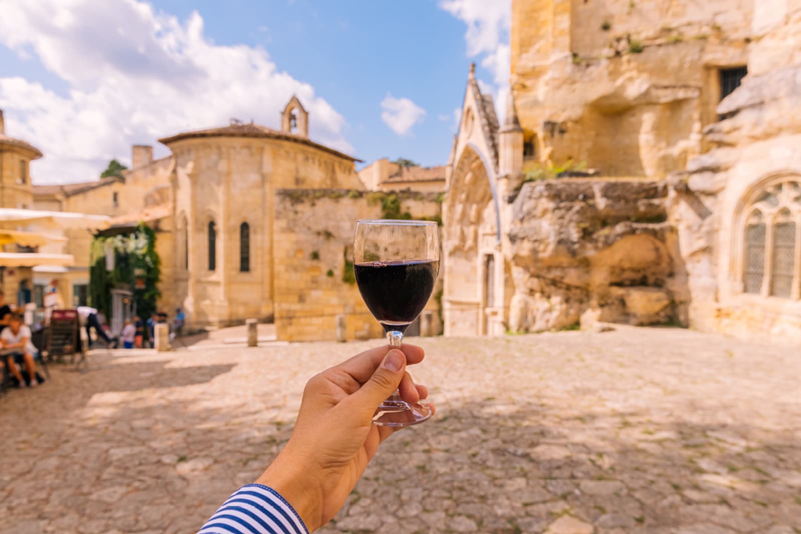 A traveller holding a glass of red wine in Bordeaux