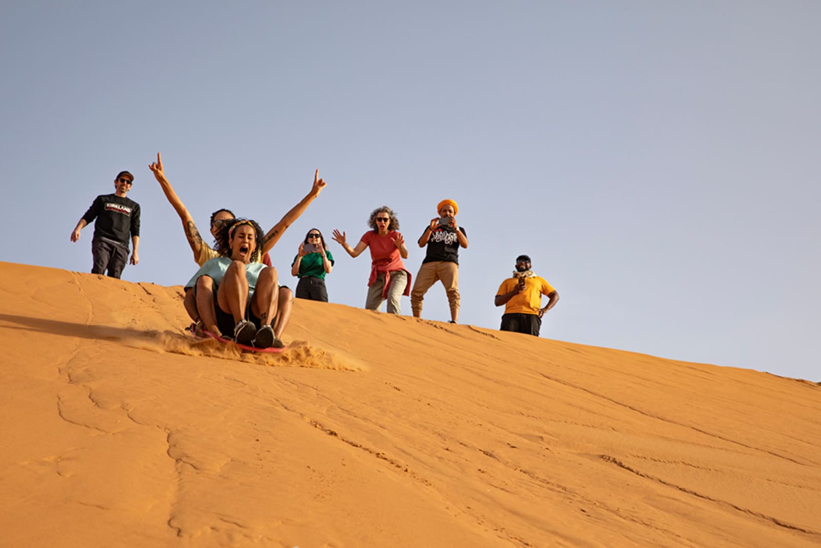 A group sledding down sand dunes in Morocco