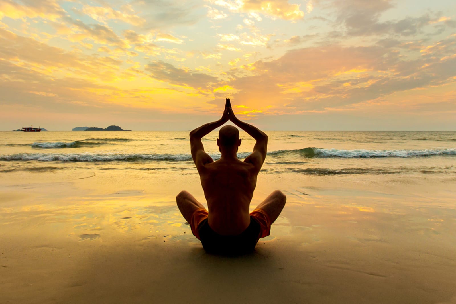 An individual practicing yoga on a beach at sunset