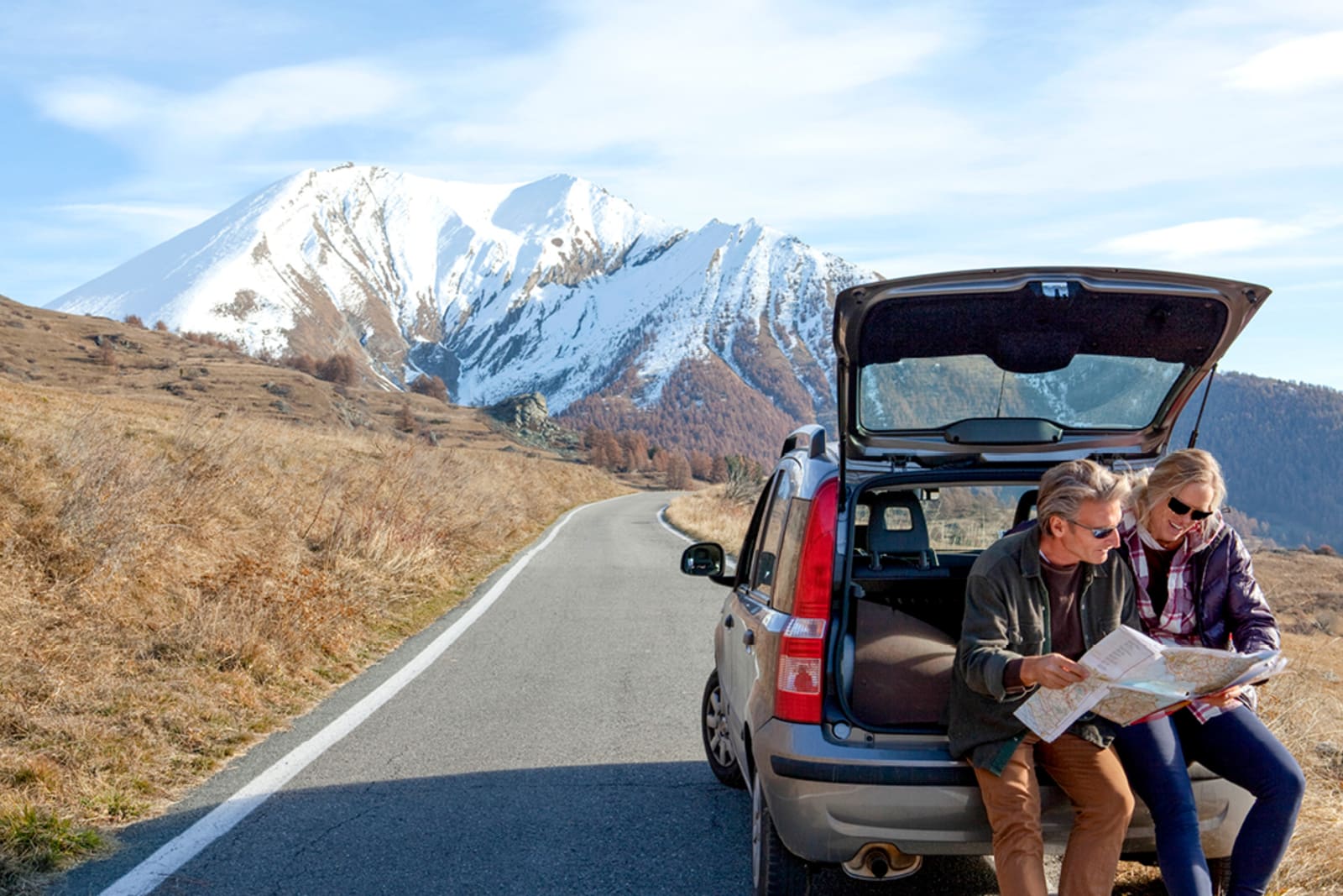 A couple checking a paper map for directions while on a road trip