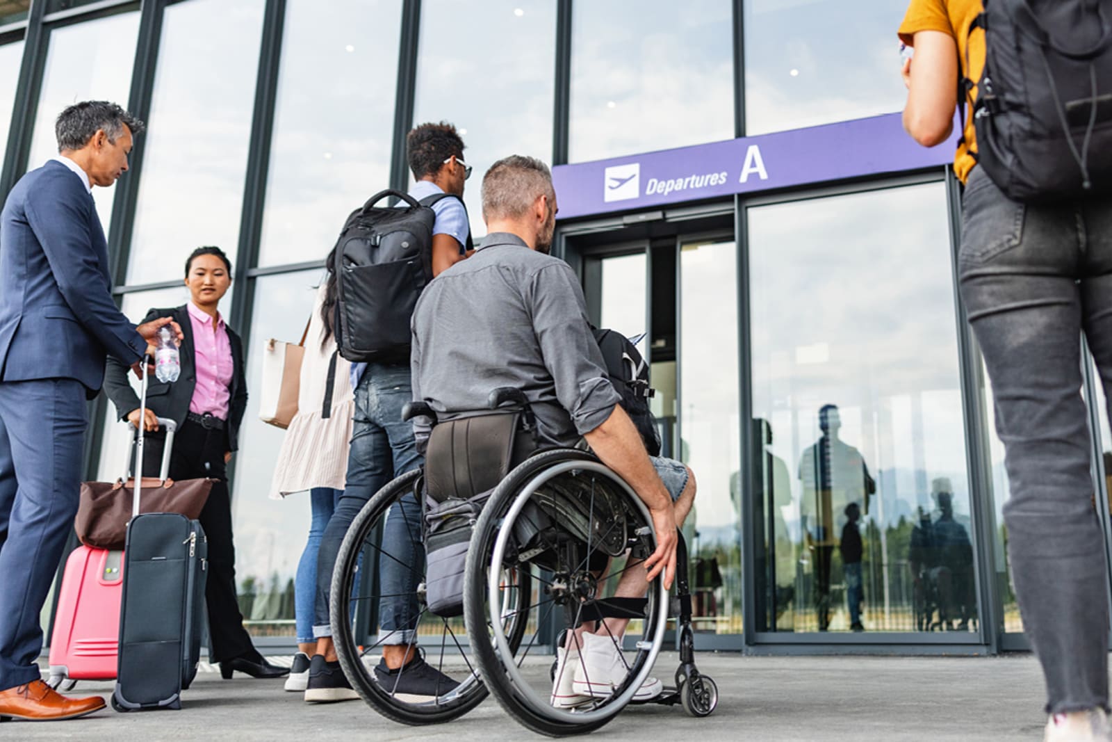 A wheelchair user entering the airport alongside other travellers