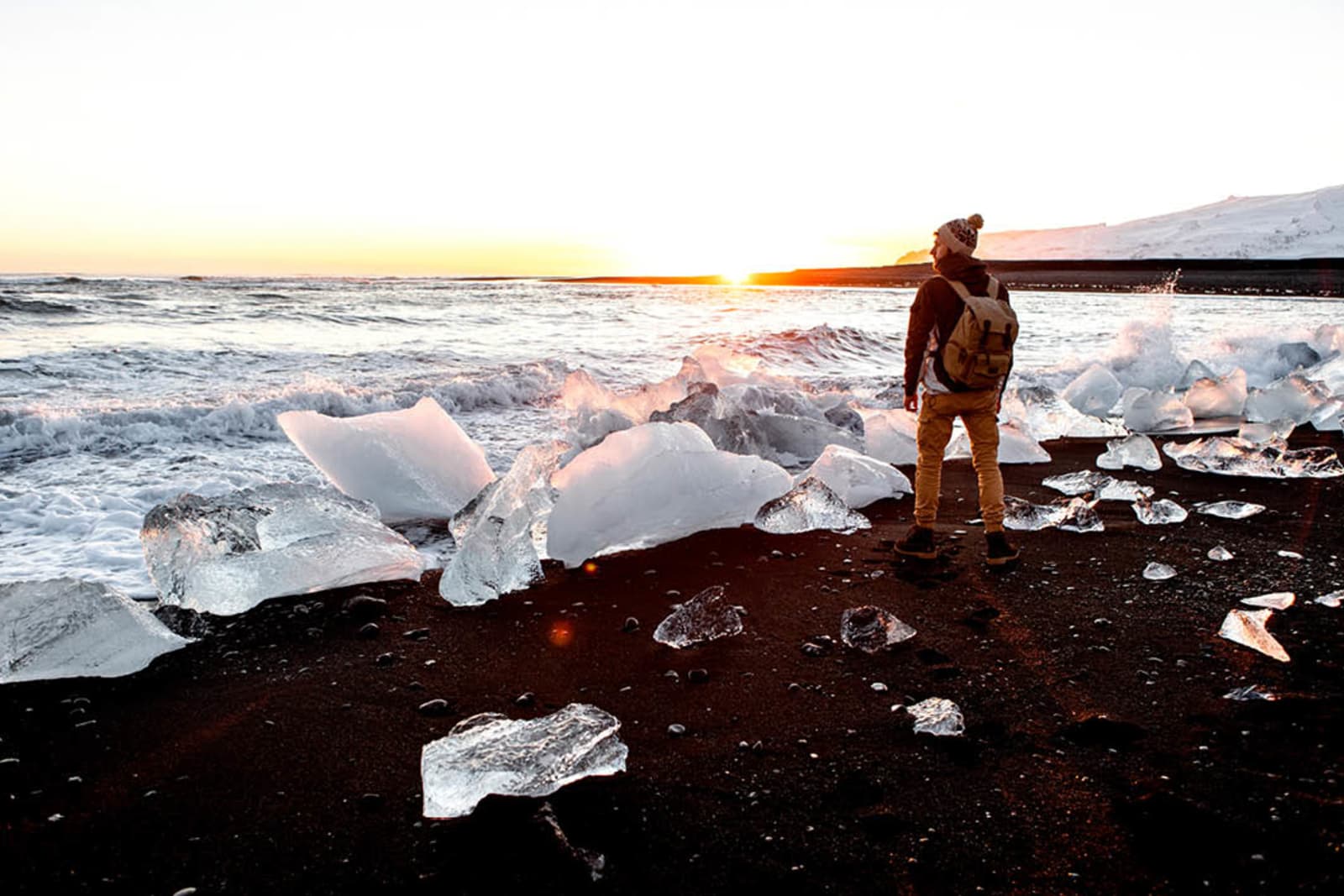 A traveller standing among the ice black on Diamond Beach in Vatnajökull National Park, Iceland