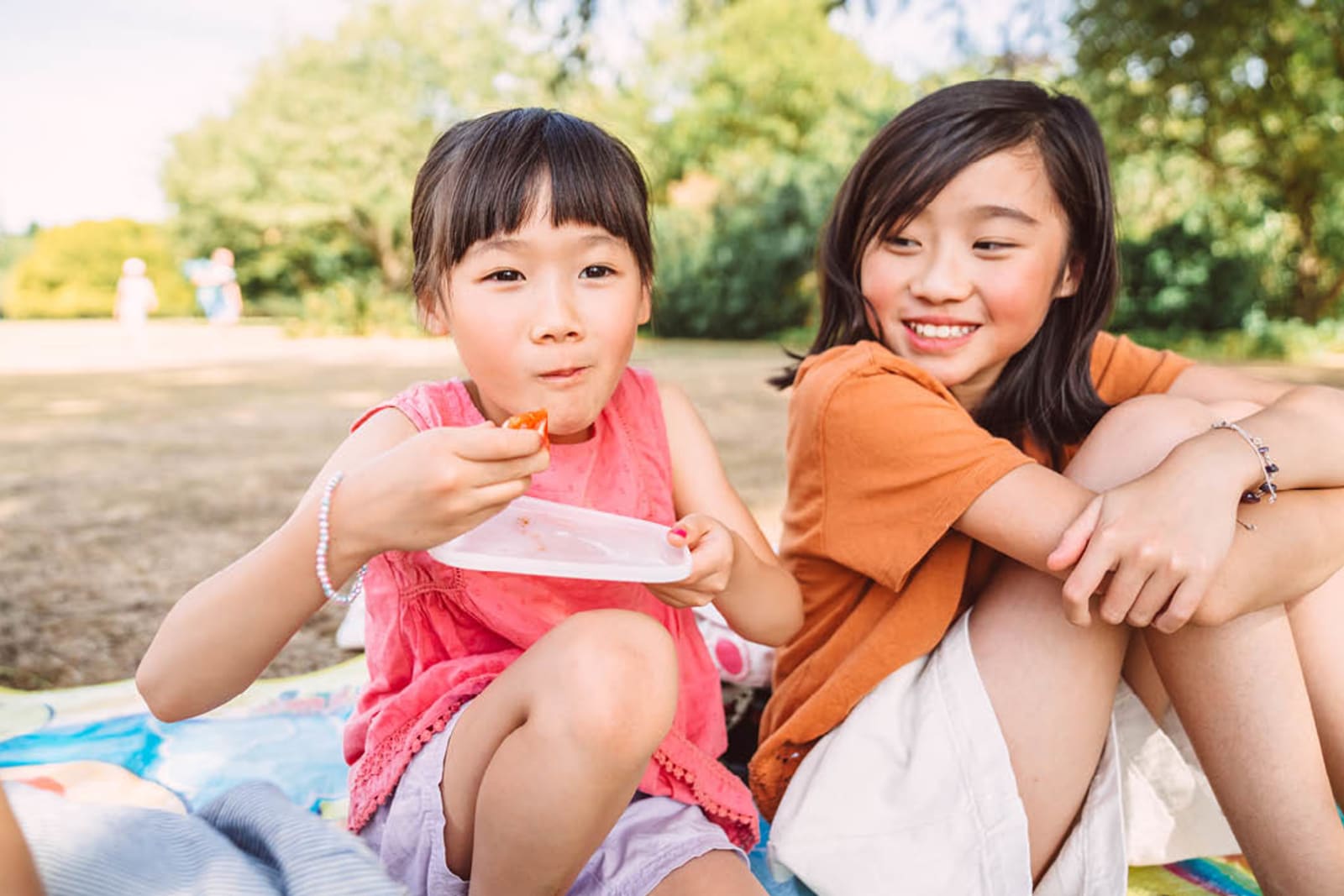 Two kids eating snacks in a park while on a family vacation