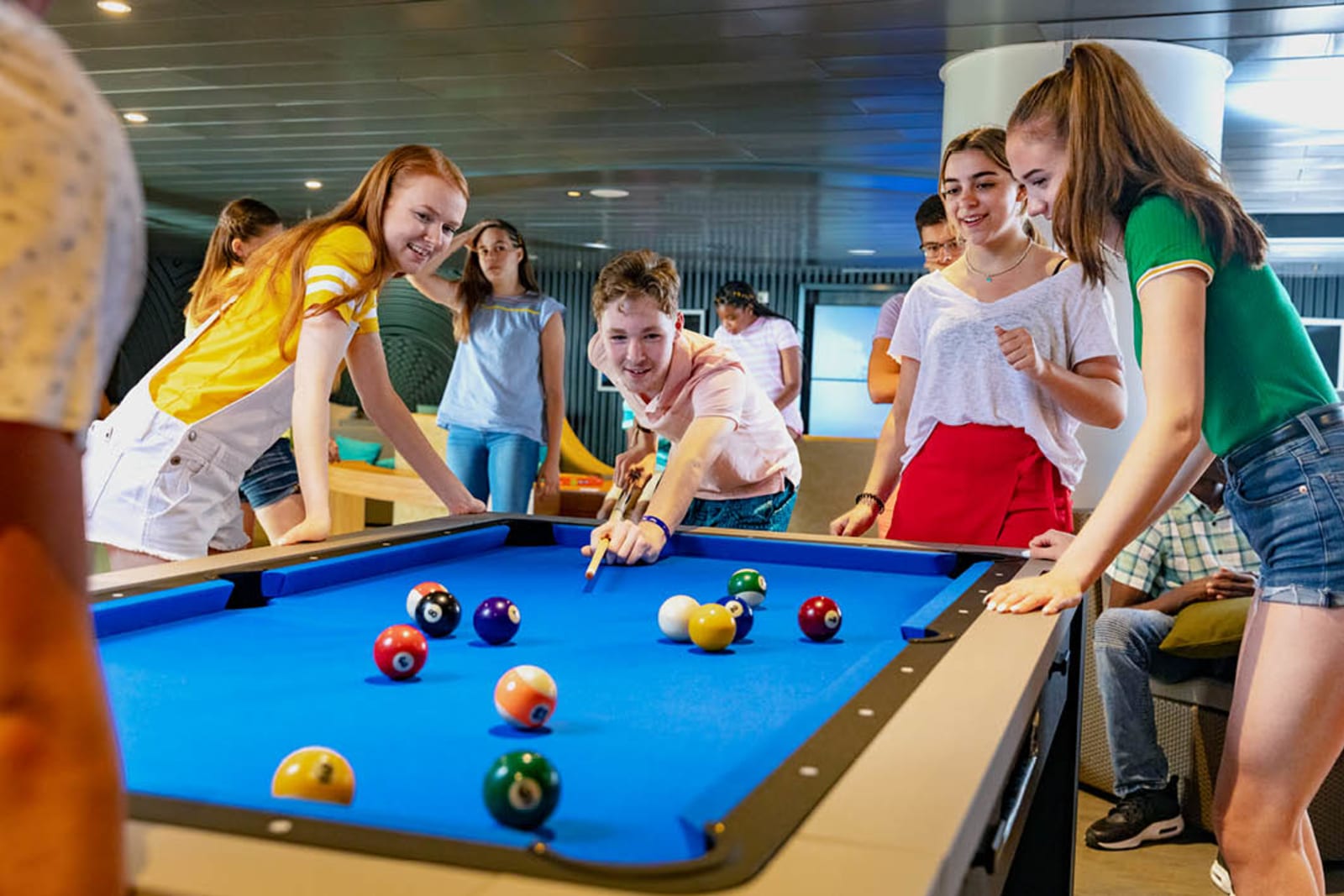 A group of teens playing pool aboard a cruise ship