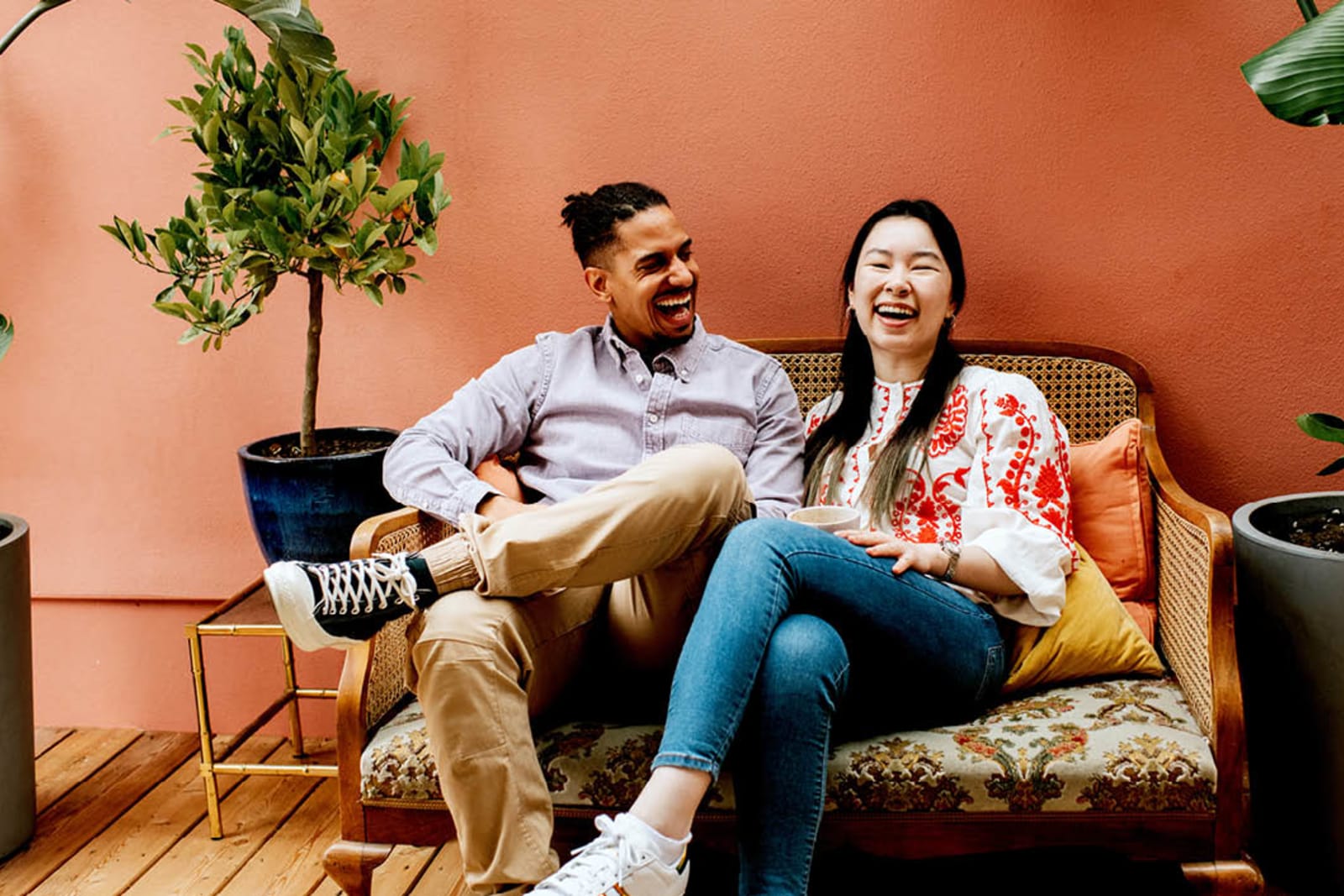 Young couple sit on a sofa and laugh together