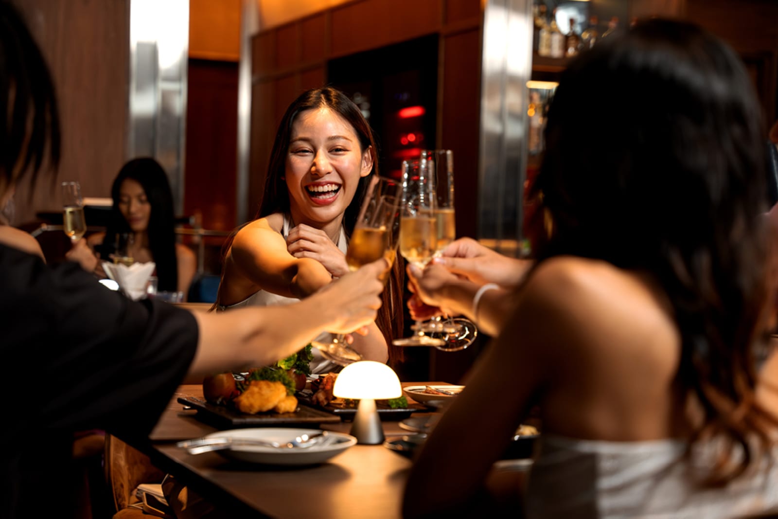 A group of girlfriends at a nice restaurant; they're celebrating with glasses of Champagne
