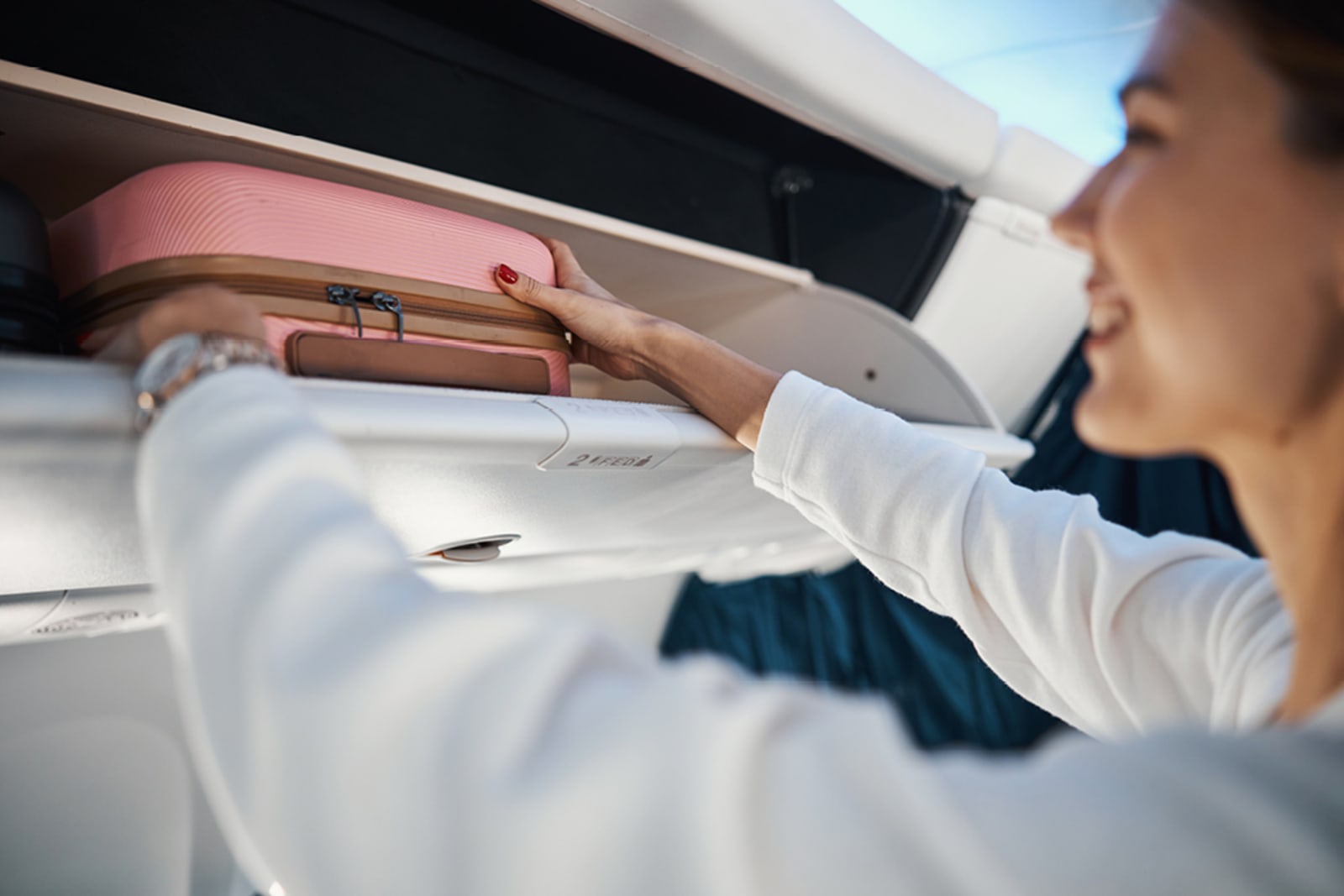 Woman putting carry-on bag in overhead bin