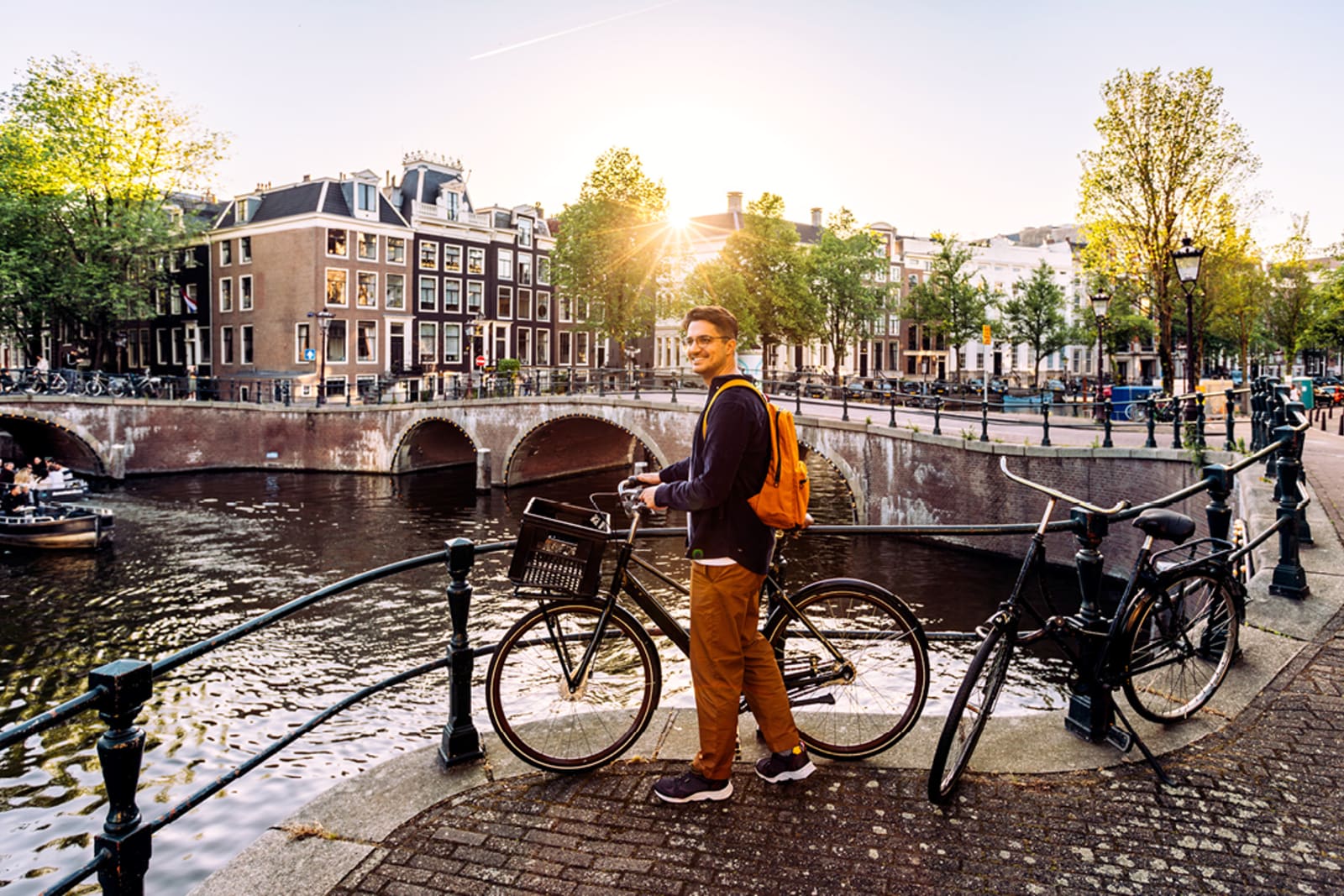 Young man with a bicycle on the canals of Amsterdam, Netherlands
