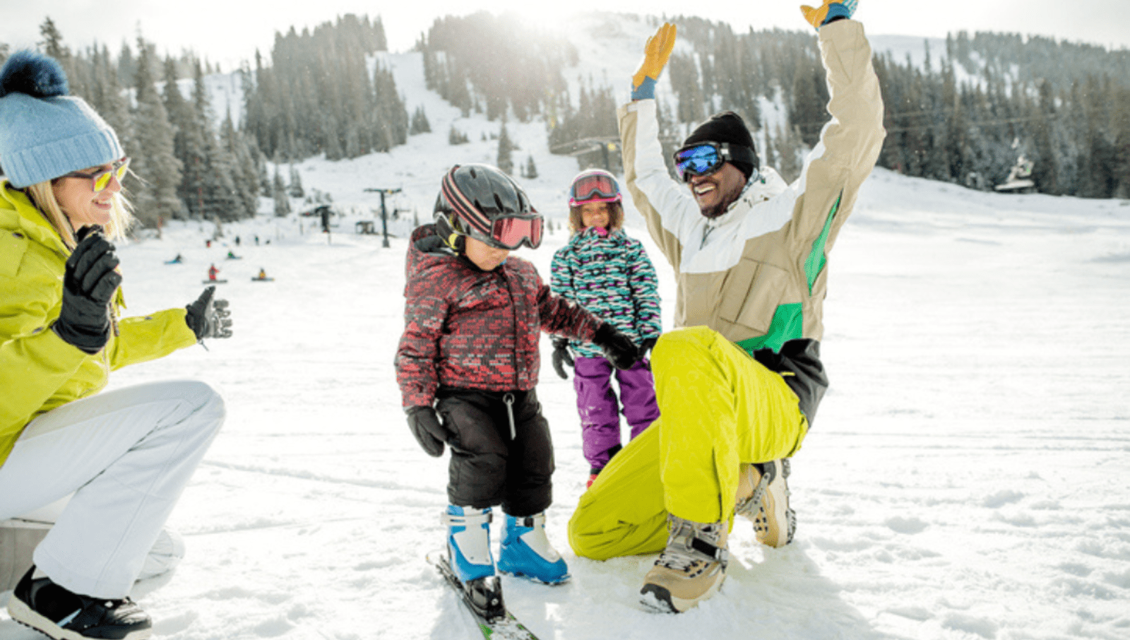 family of two adults and two children with ski equipment in the snow 