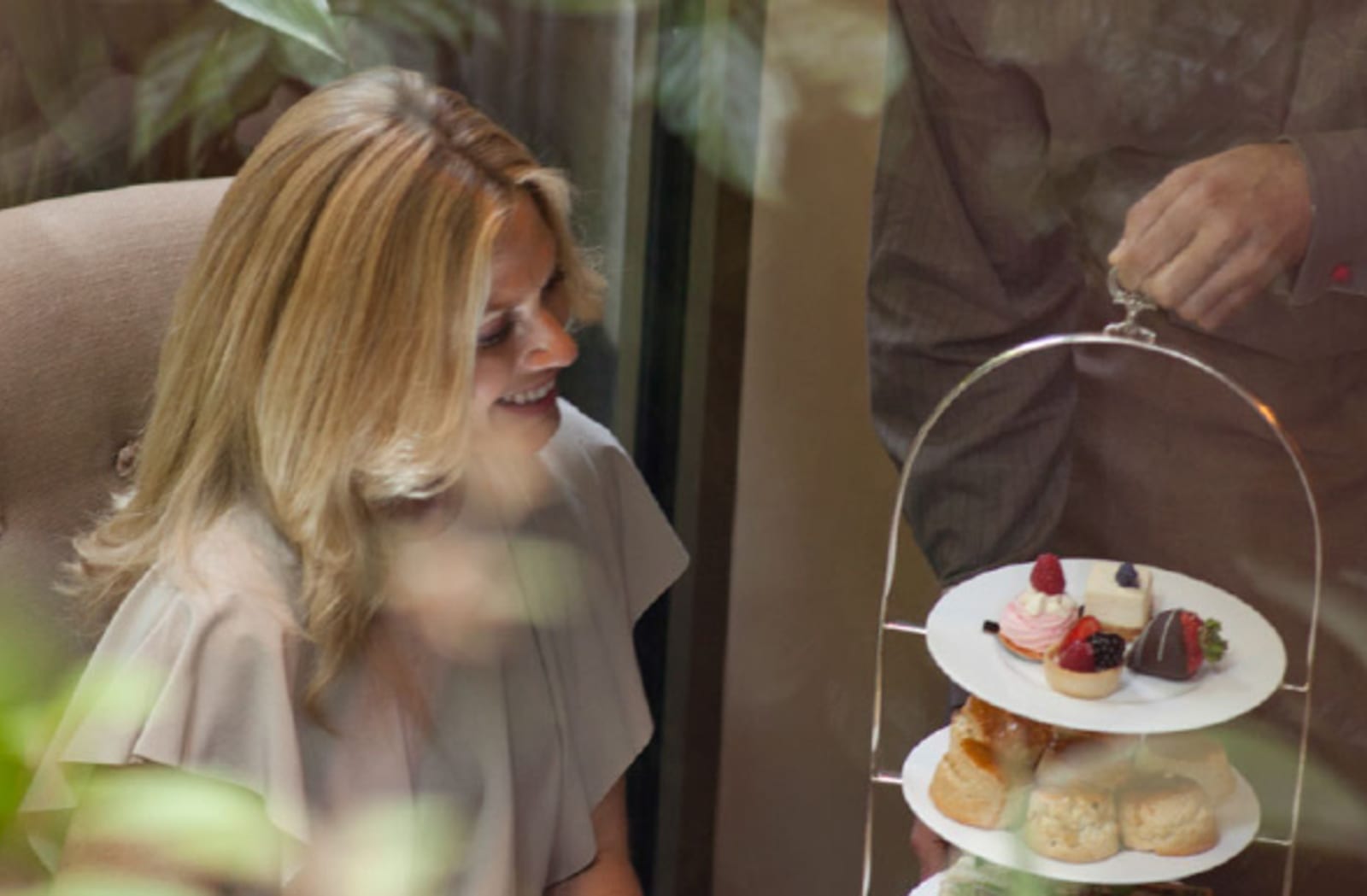 Blonde woman smiling at a high-tea tray