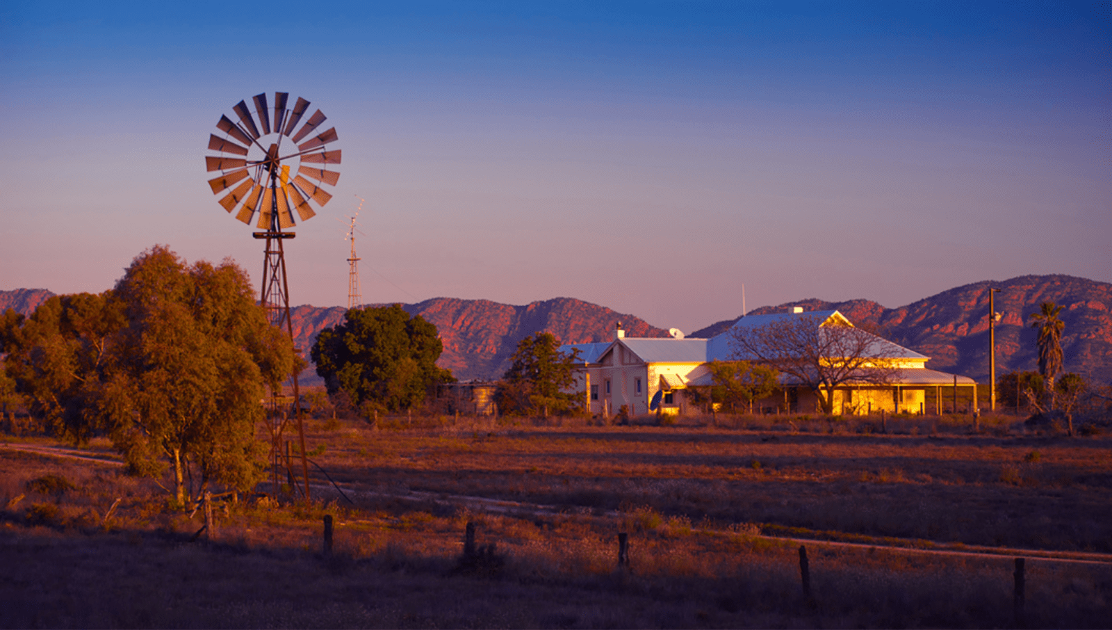 Farm and windmill with Flinders Ranges in background at sunset 