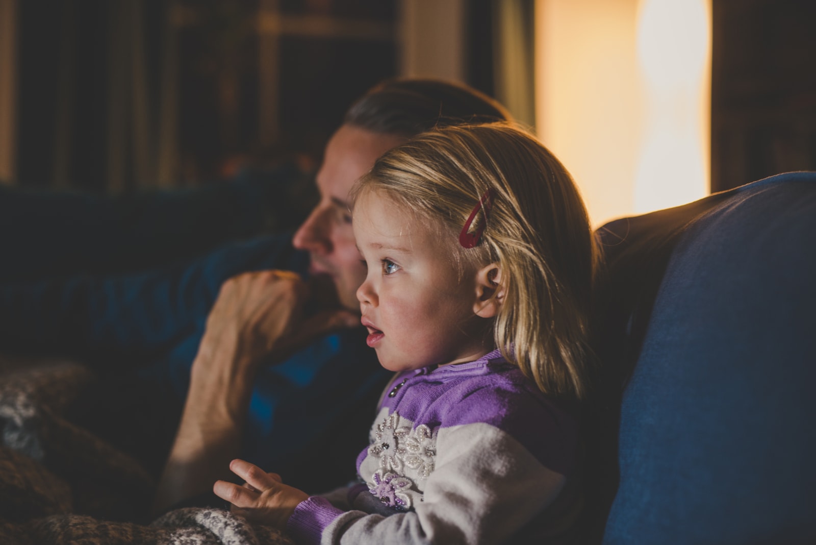 father and daughter sitting on couch watching TV together