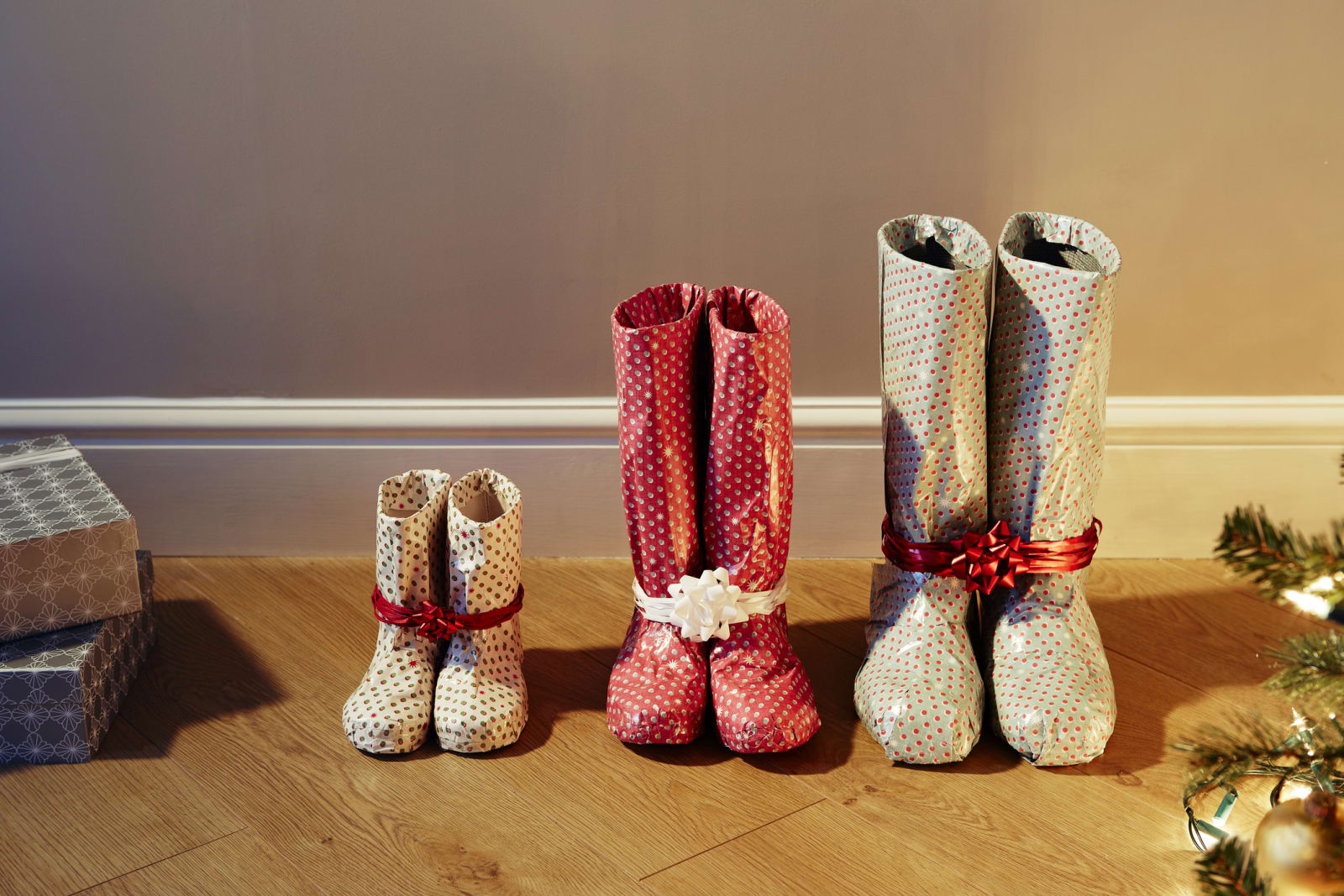 three pairs of shoes wrapped in paper by christmas tree