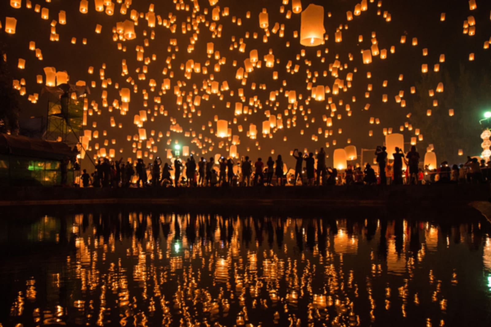thousands of lanterns in sky at night reflected in water in Thailand