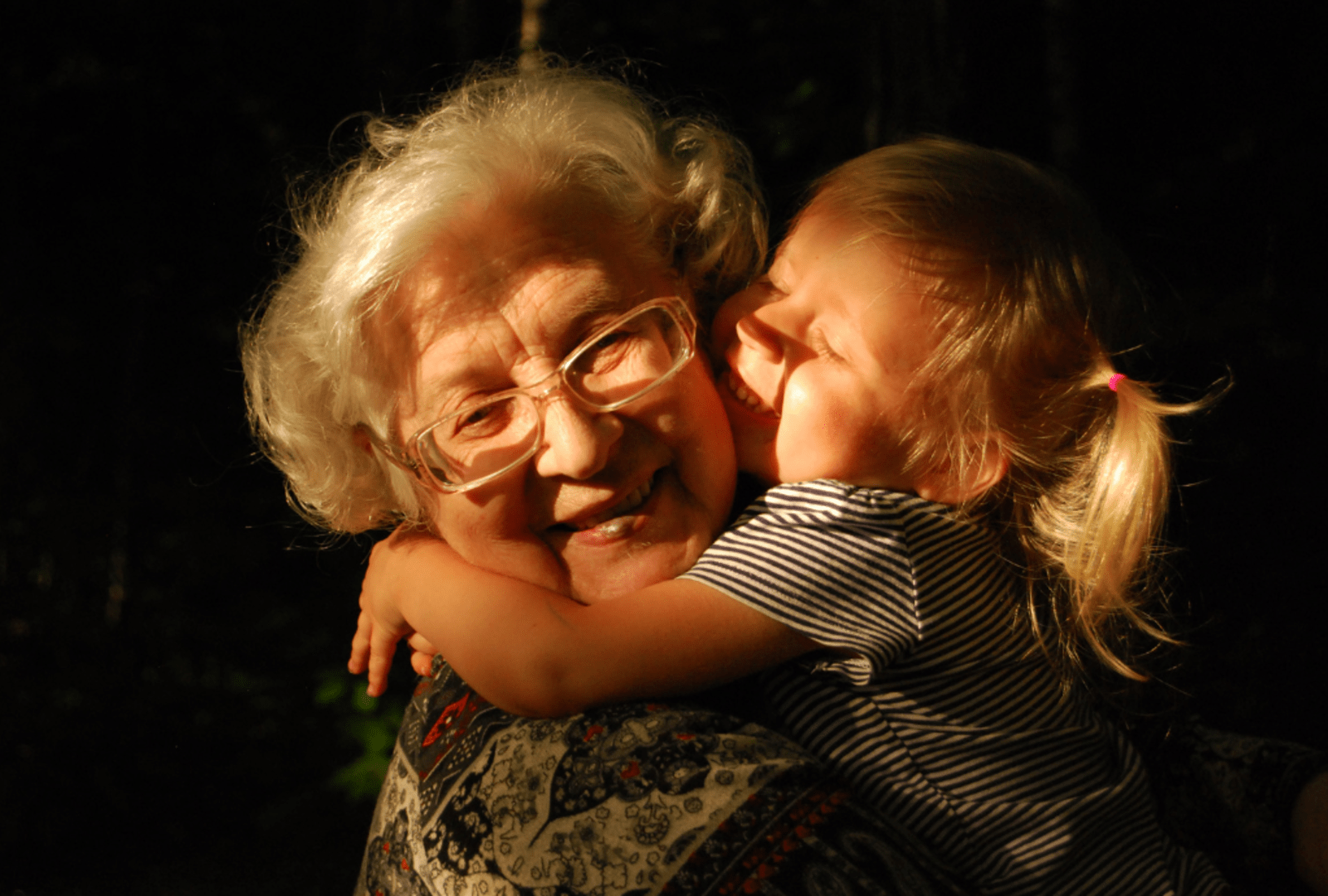 A young girl cuddles an old woman