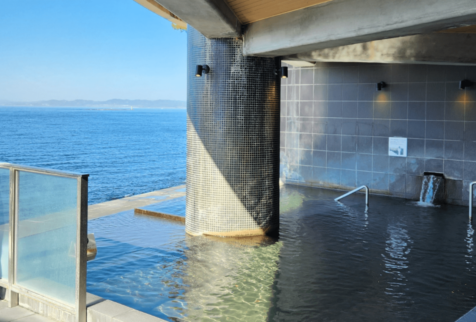 An open-air Japanese onsen hot spring pool overlooking the sea