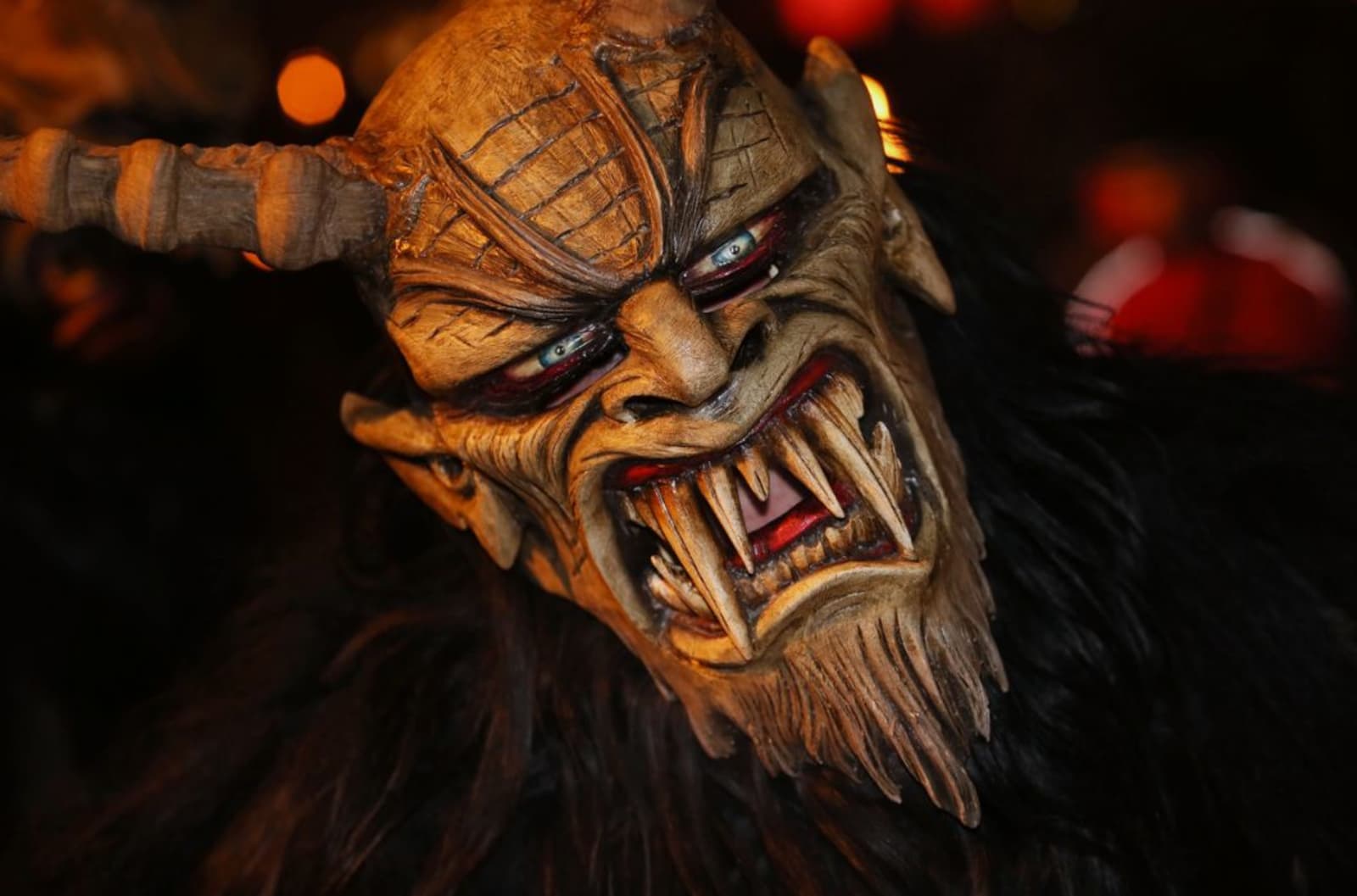 A person wearing a Krampus costume with large horns, sharp teeth and long hair.