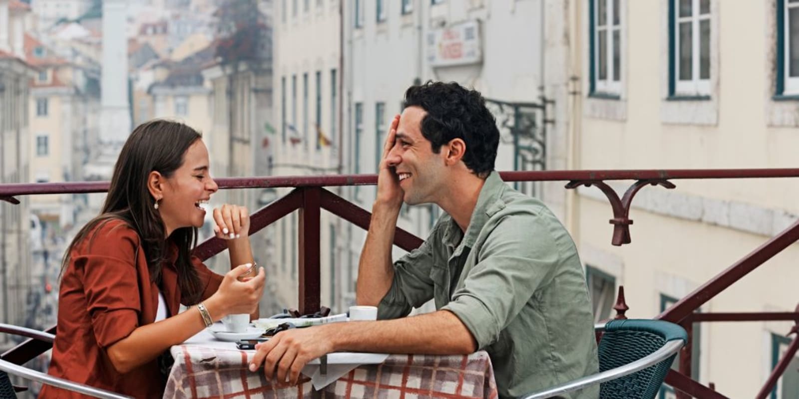 A couple on a balcony having a romantic dinner and laughing together