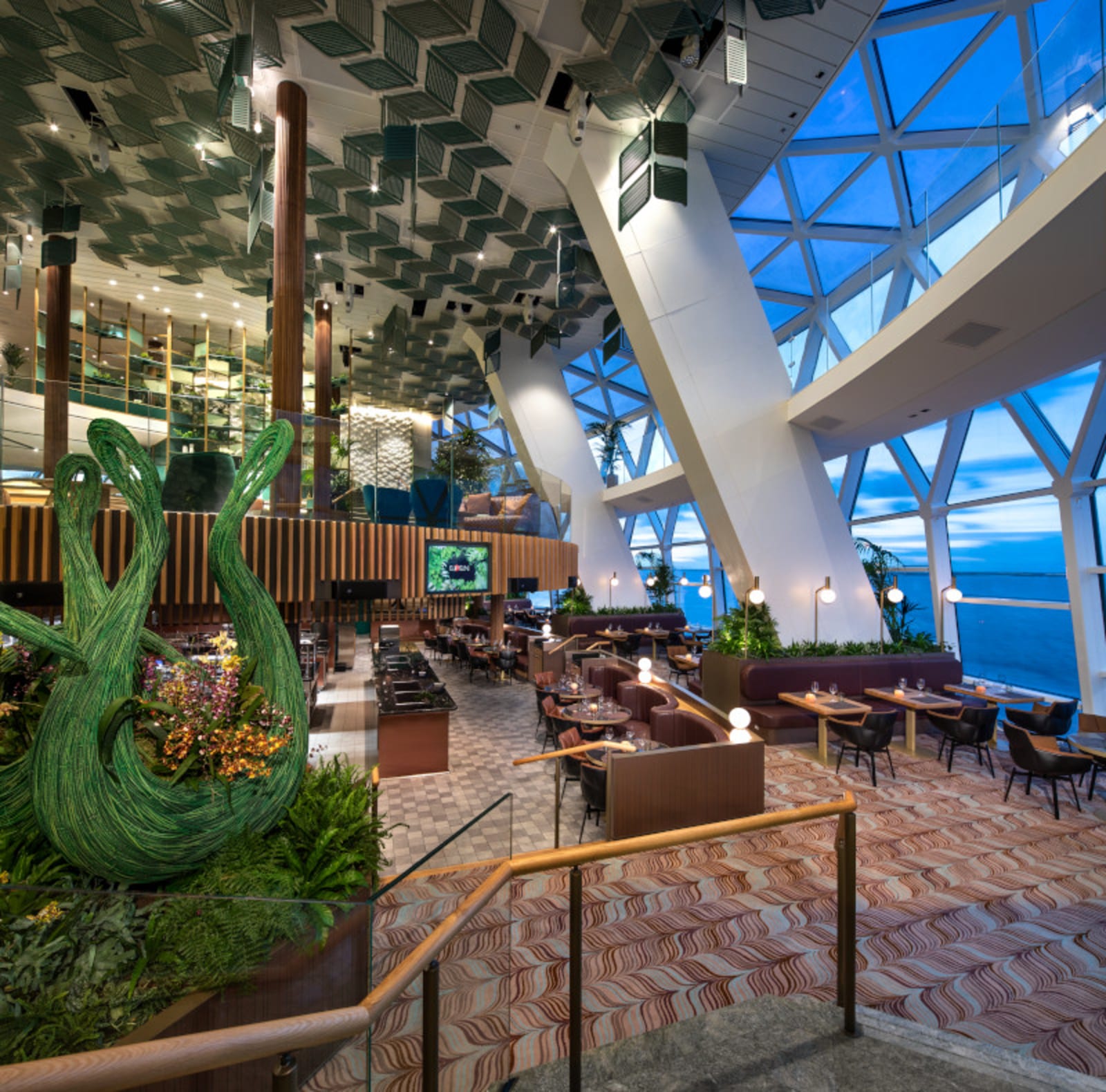 Cruise ship restaurant - open kitchen, open triangle windows and leather seating lit by round warm lights