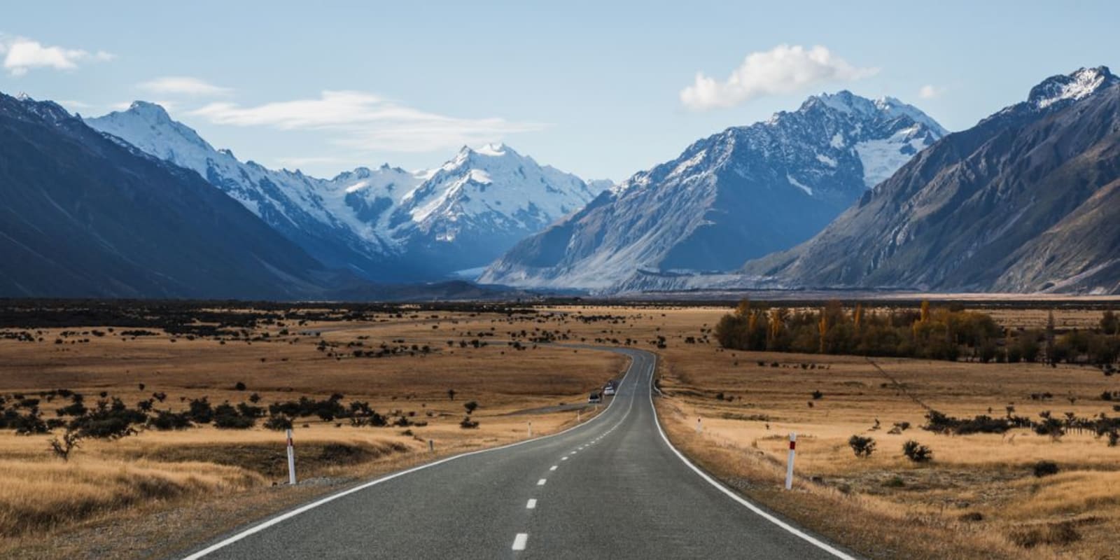 A long straight road heading towards snowcapped mountains in New Zealand
