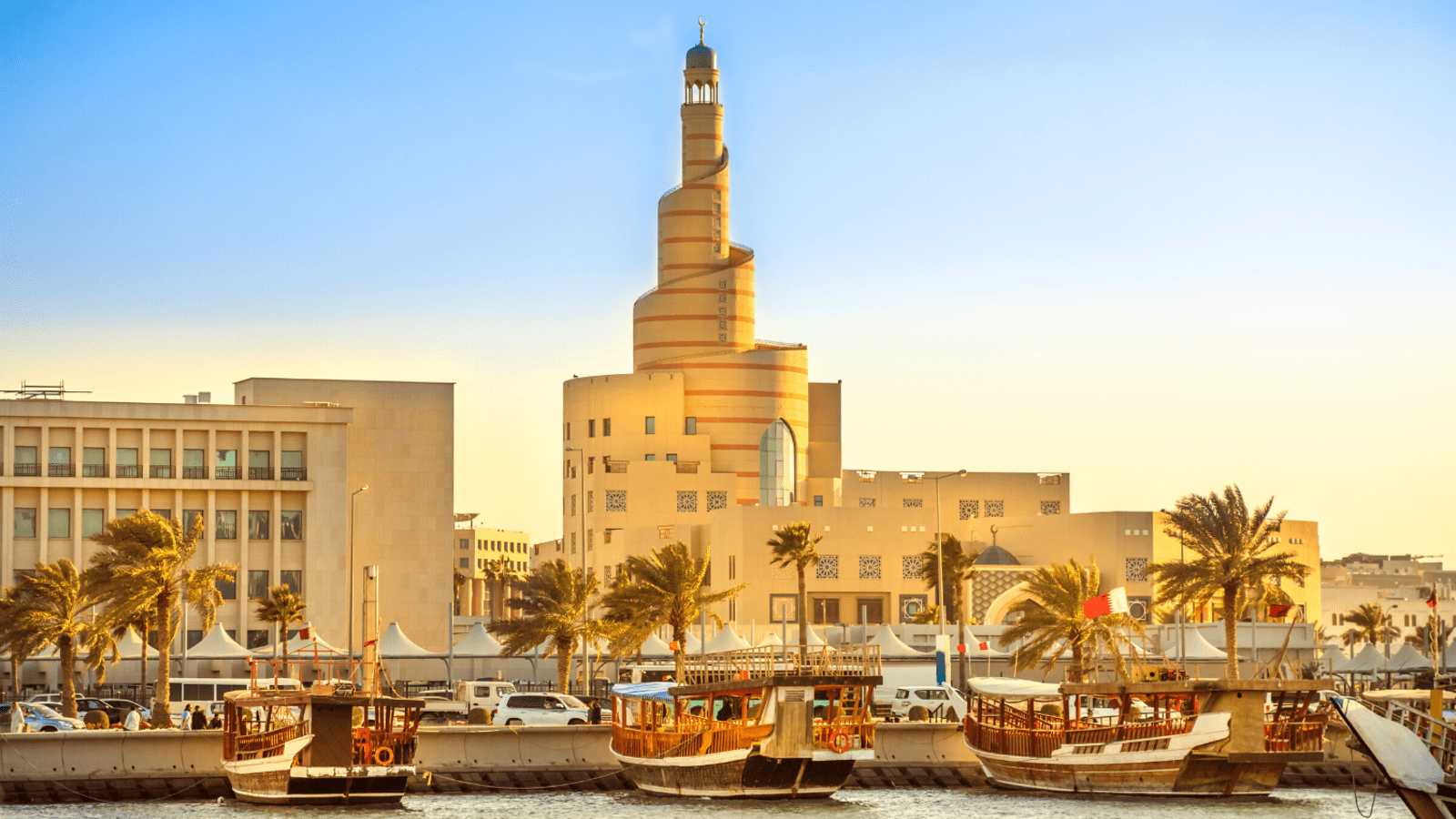 Unique spiral architecture on the waterfront in Qatar lined by palm trees and boats