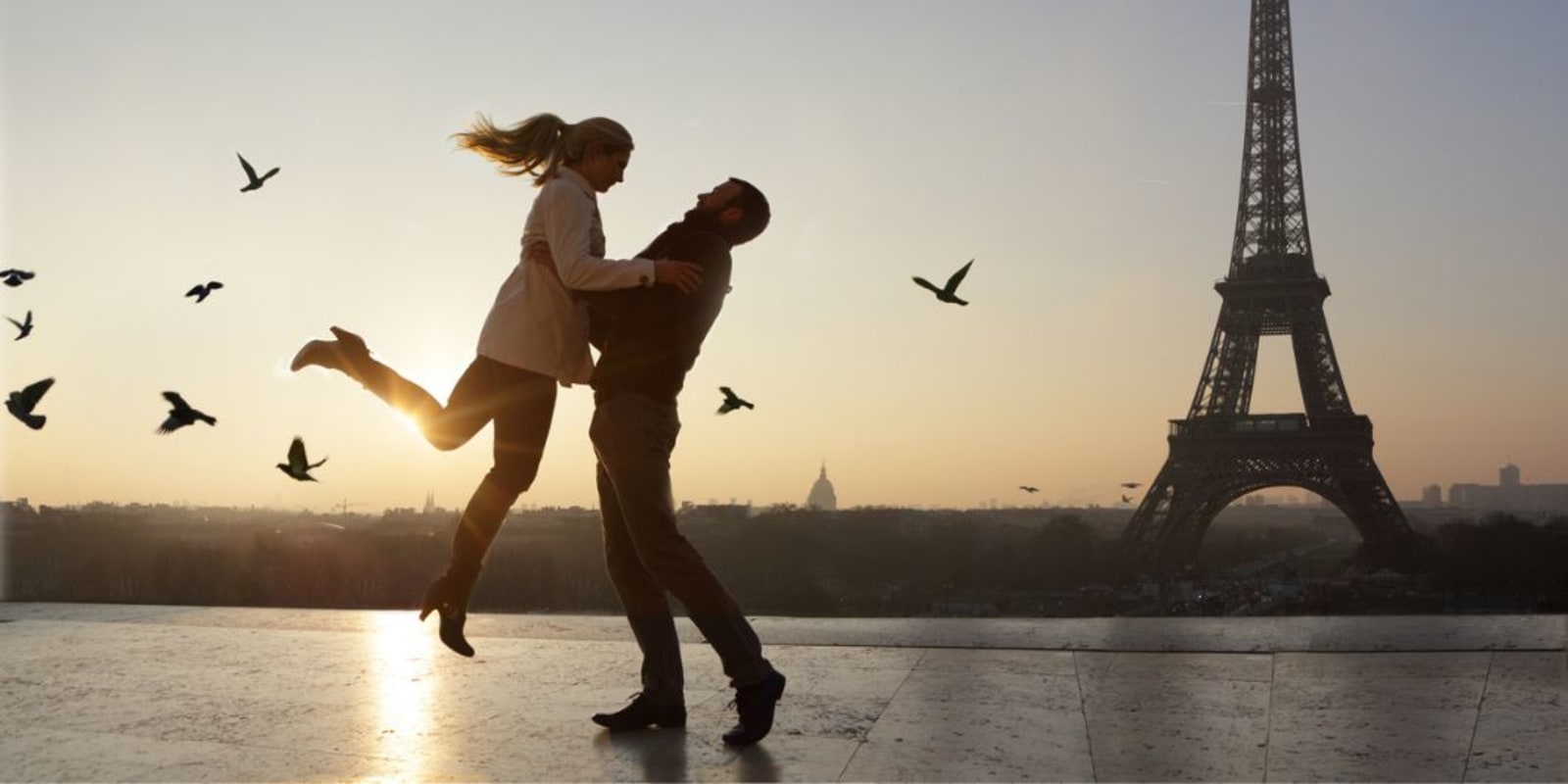 A couple dancing romantically in front of the Eiffel Tower.