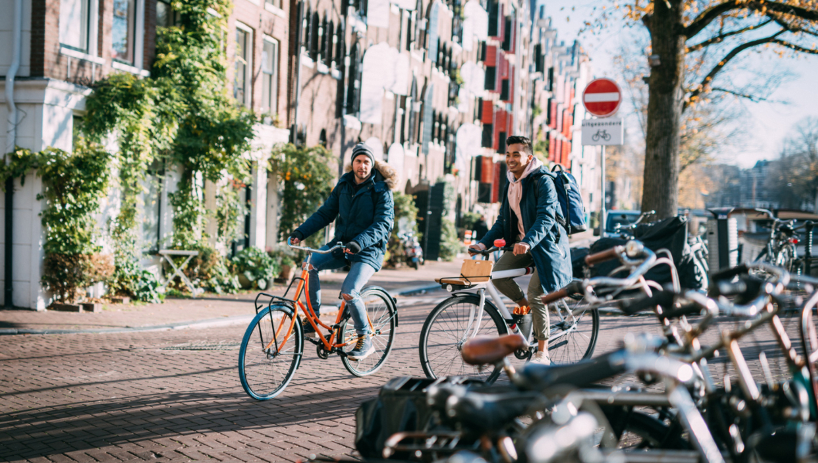 two men riding bikes through streets of amsterdam