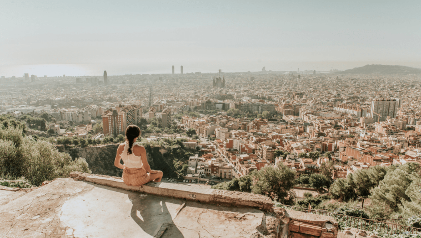 lady sitting on edge of cliff looking over barcelona city