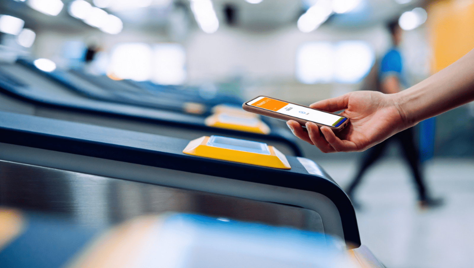 Person holding their phone out onto a sensor to enter train gates to get into station