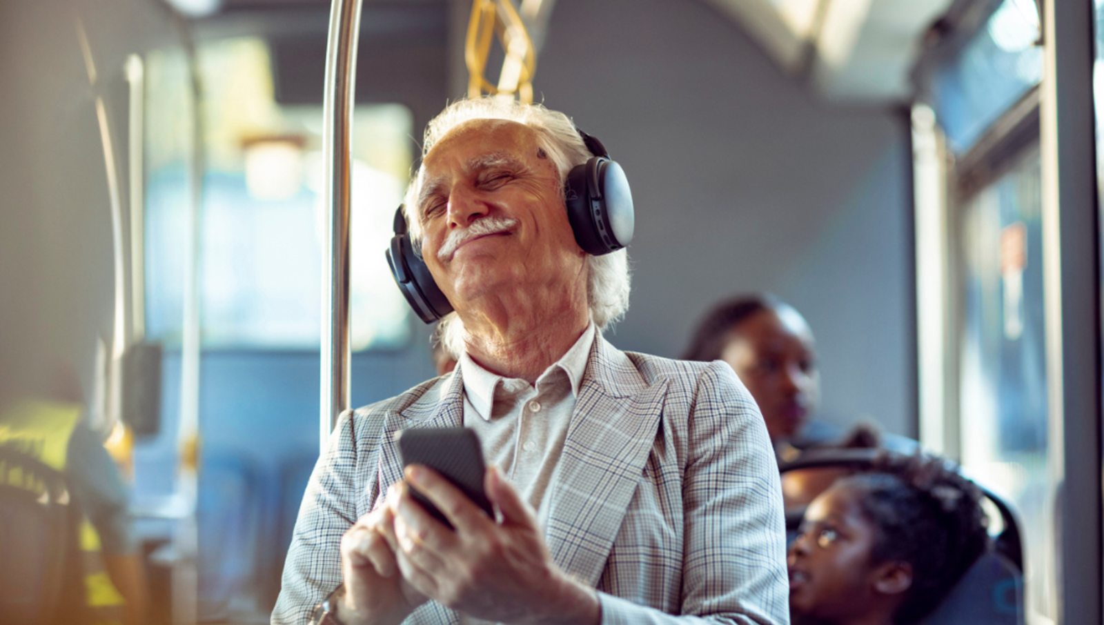 Old man happily listening to music with headphones on on a bus