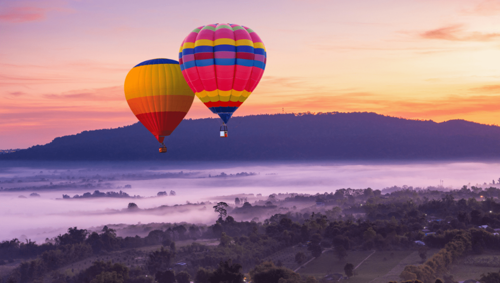 Two colourful hot air balloons flying over thailand at dusk